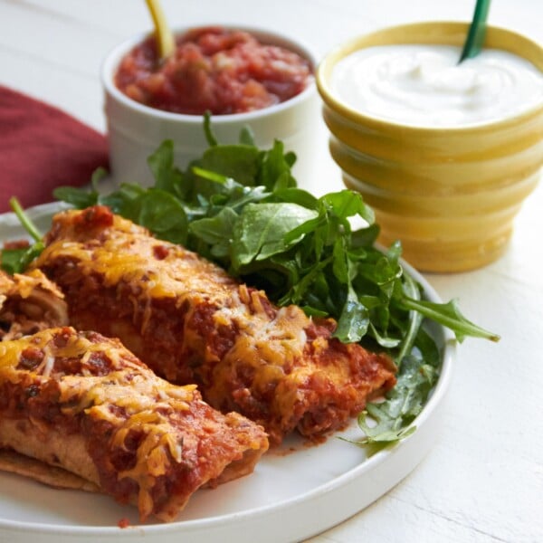 Spicy Chicken and Black Bean Enchiladas on white plate.