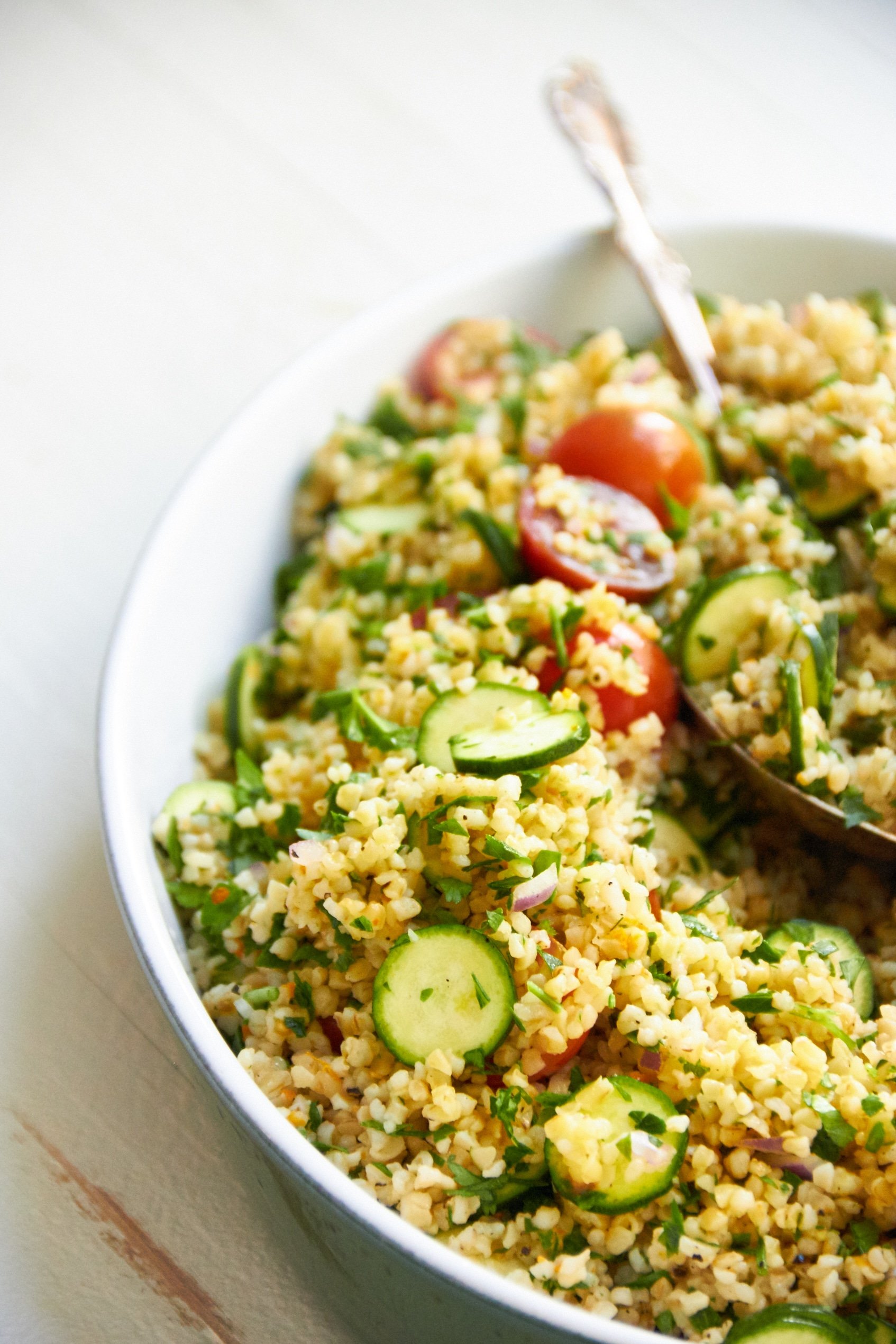 Serving bowl and spoon with Tomato, Zucchini and Bulgur Salad..