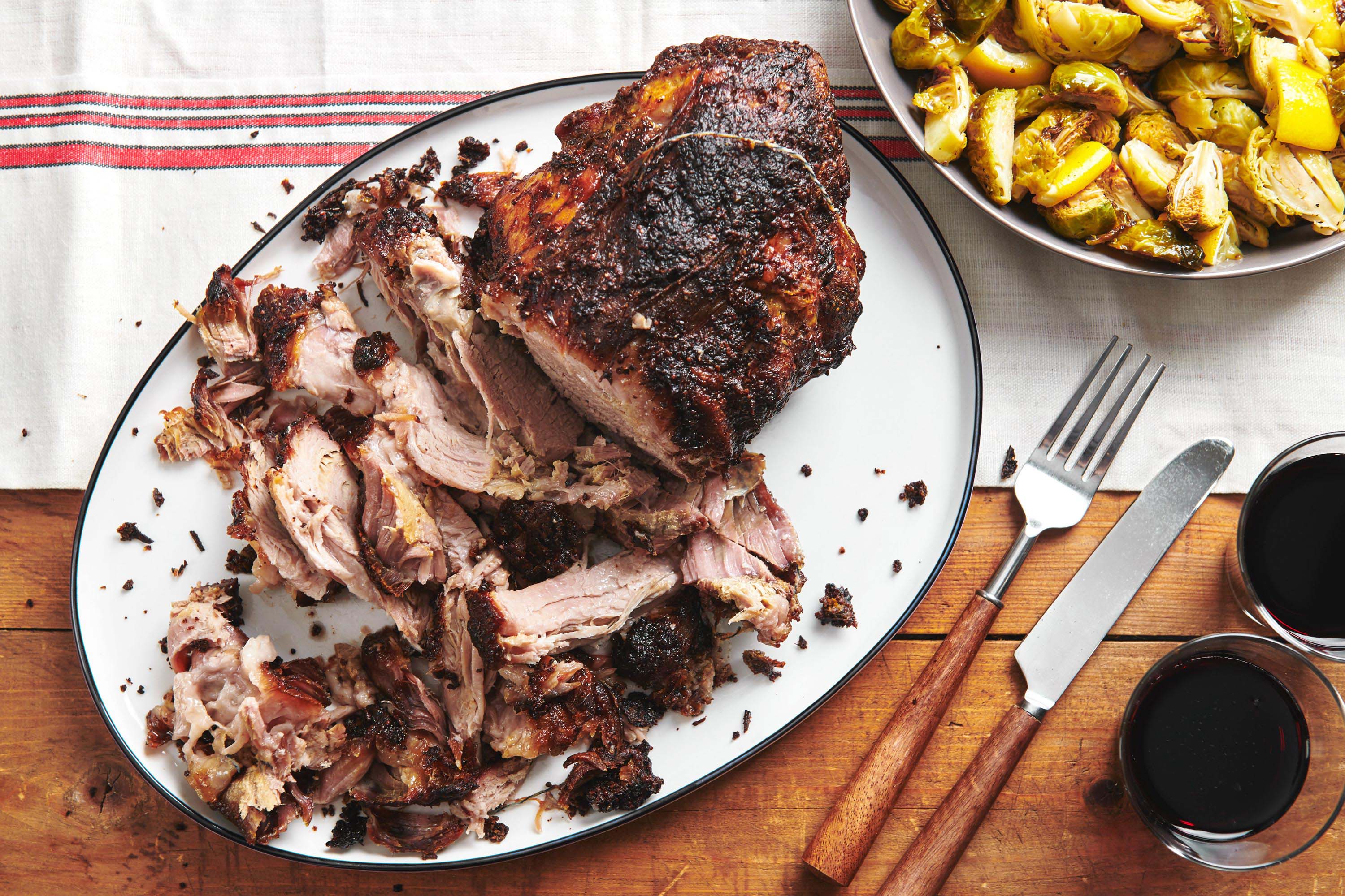Sliced Fall-Apart Roasted Pork Shoulder with Rosemary, Mustard and Garlic on serving plate.