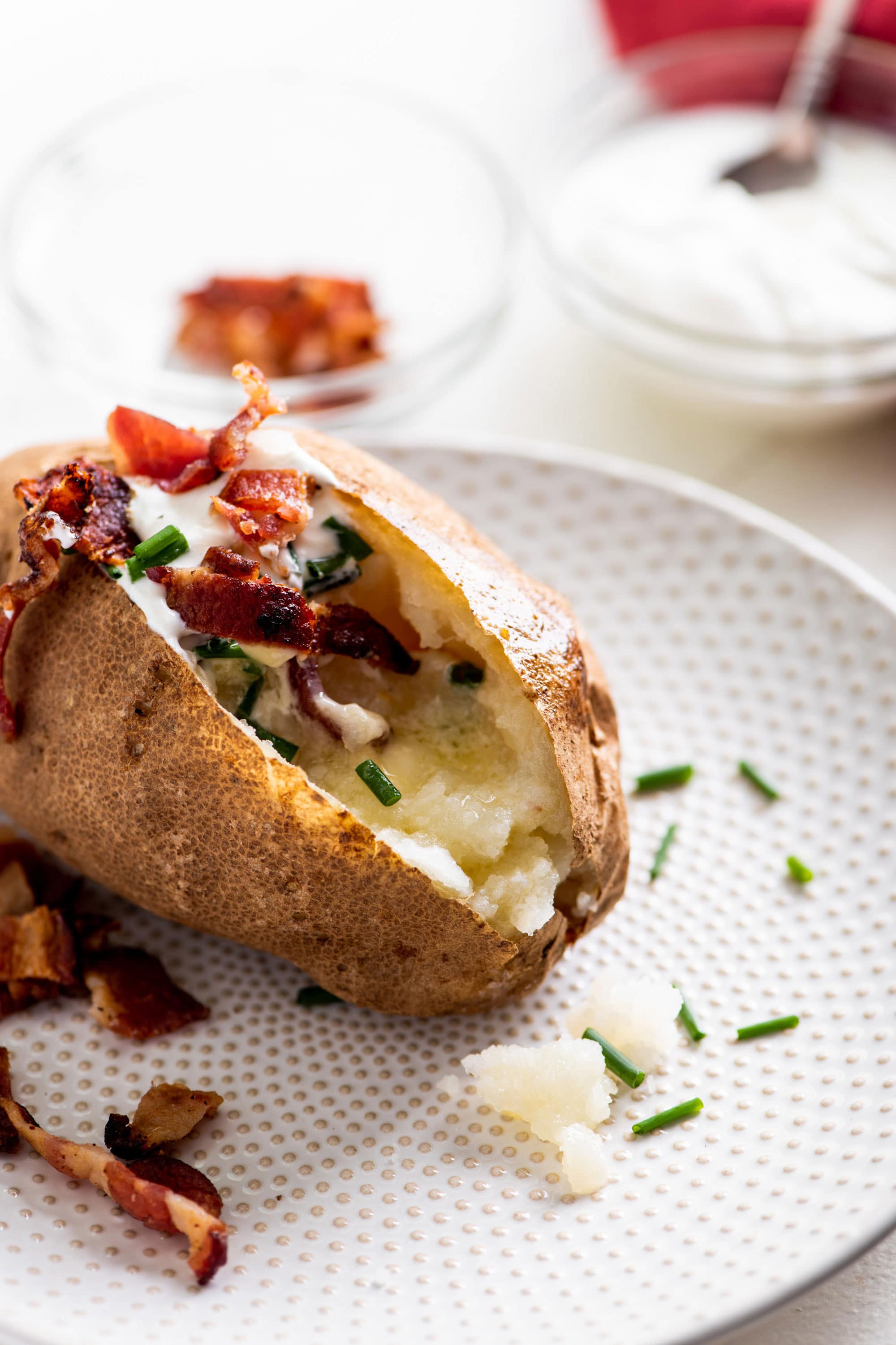 Fully loaded baked potato on a white plate.