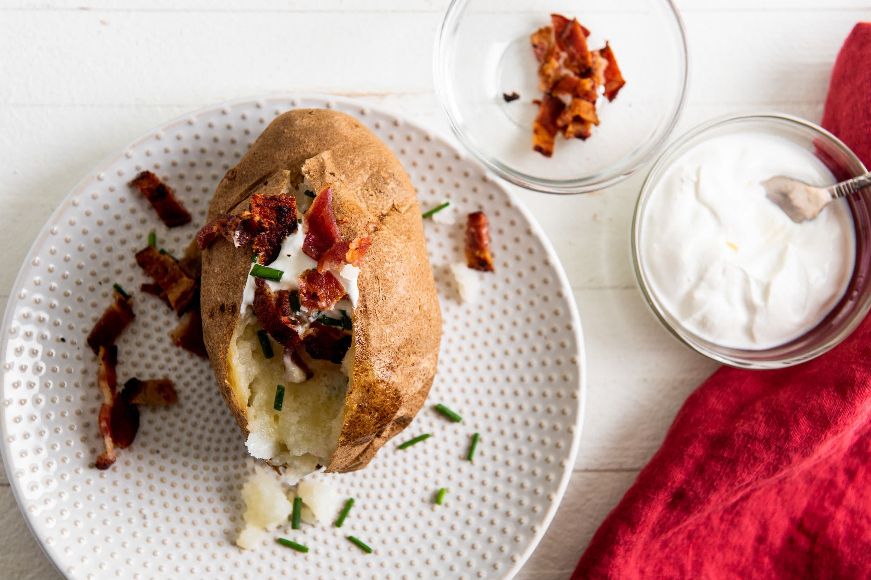 Fully loaded baked potato on a white plate.