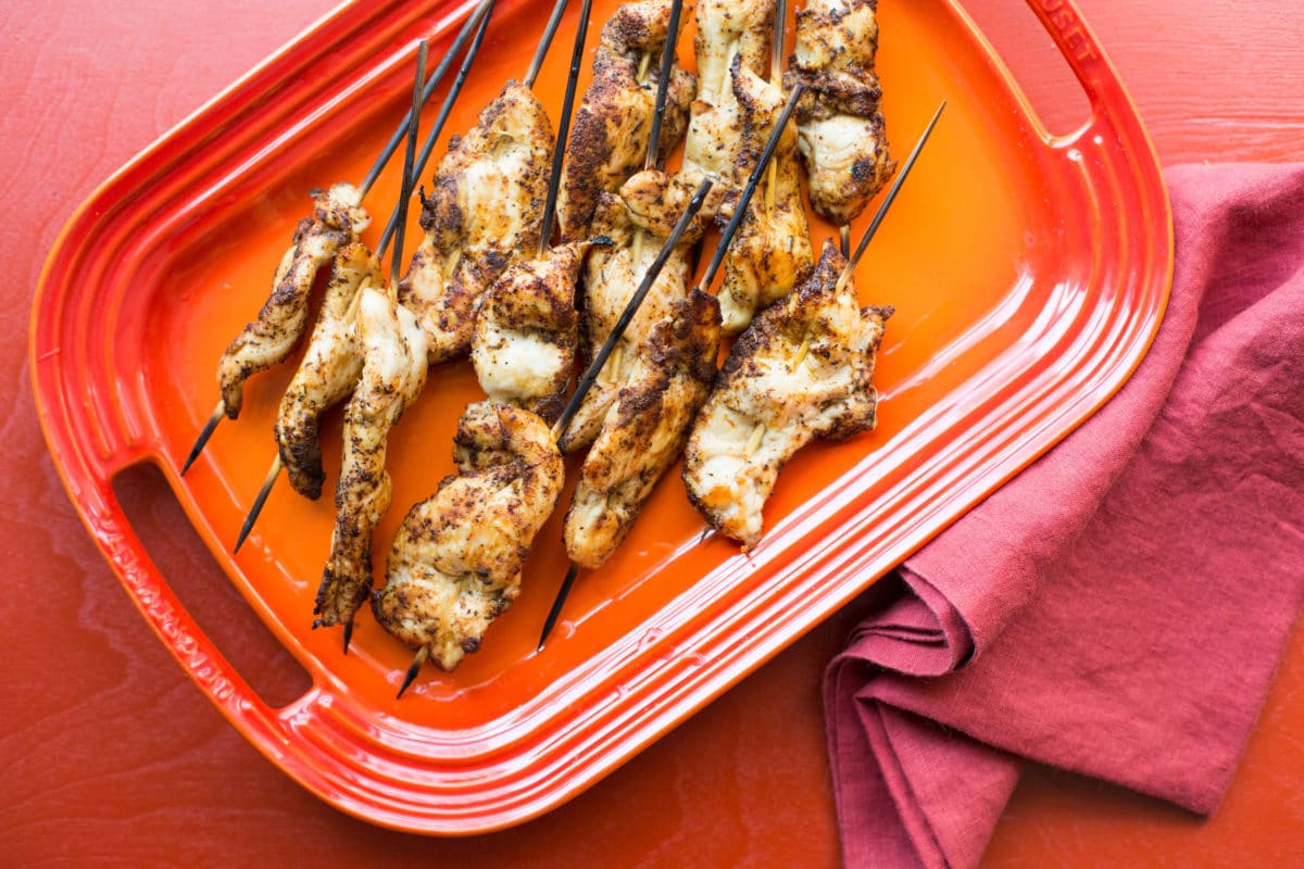 Orange platter piled with Chicken Tender Skewers with Spiced Curry Rub.