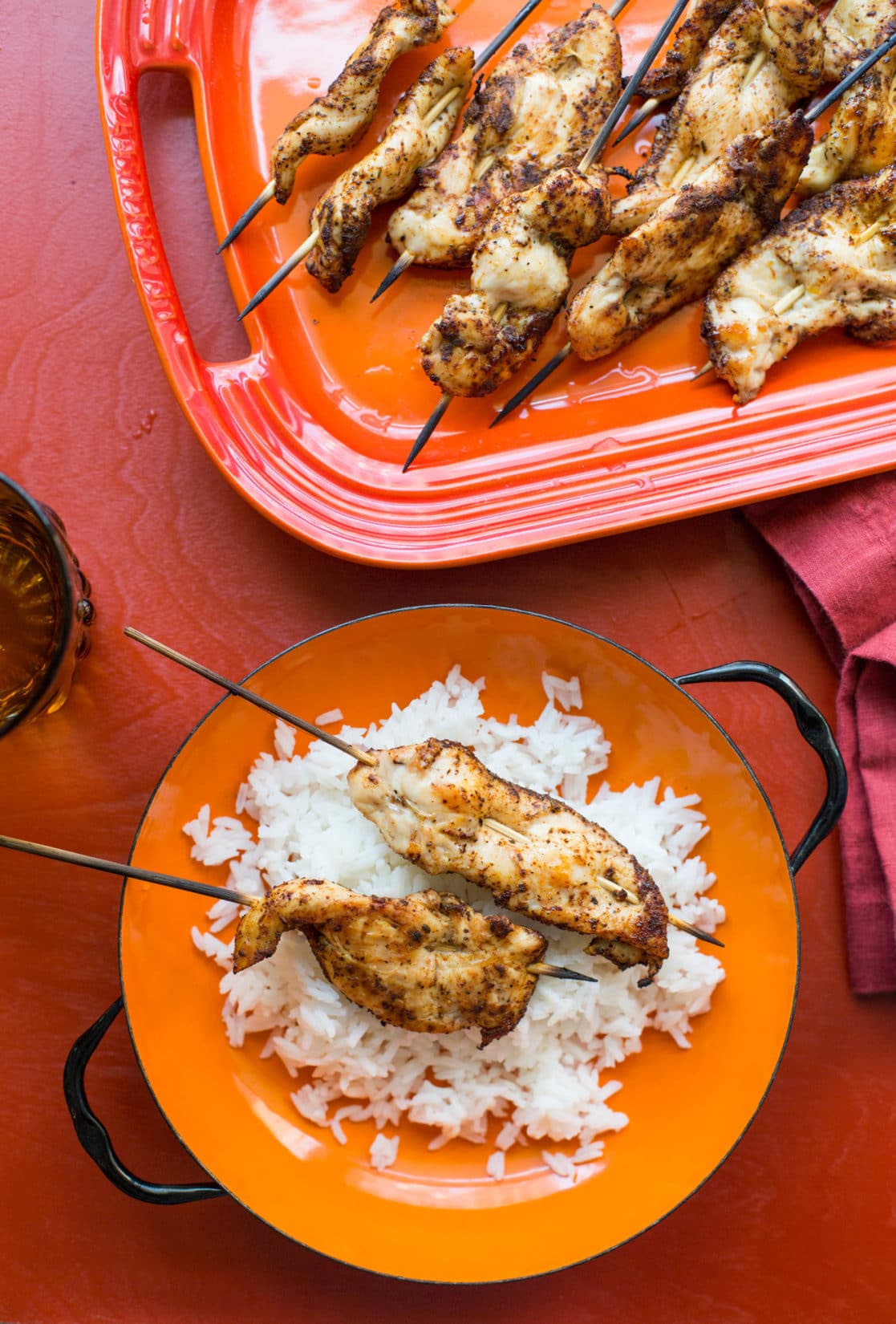 Orange plate with rice and Chicken Tender Skewers with Spiced Curry Rub.