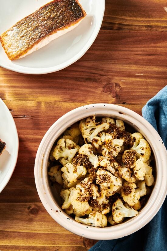 Pot of Sautéed Cauliflower with Mustard Seeds on a wooden table.