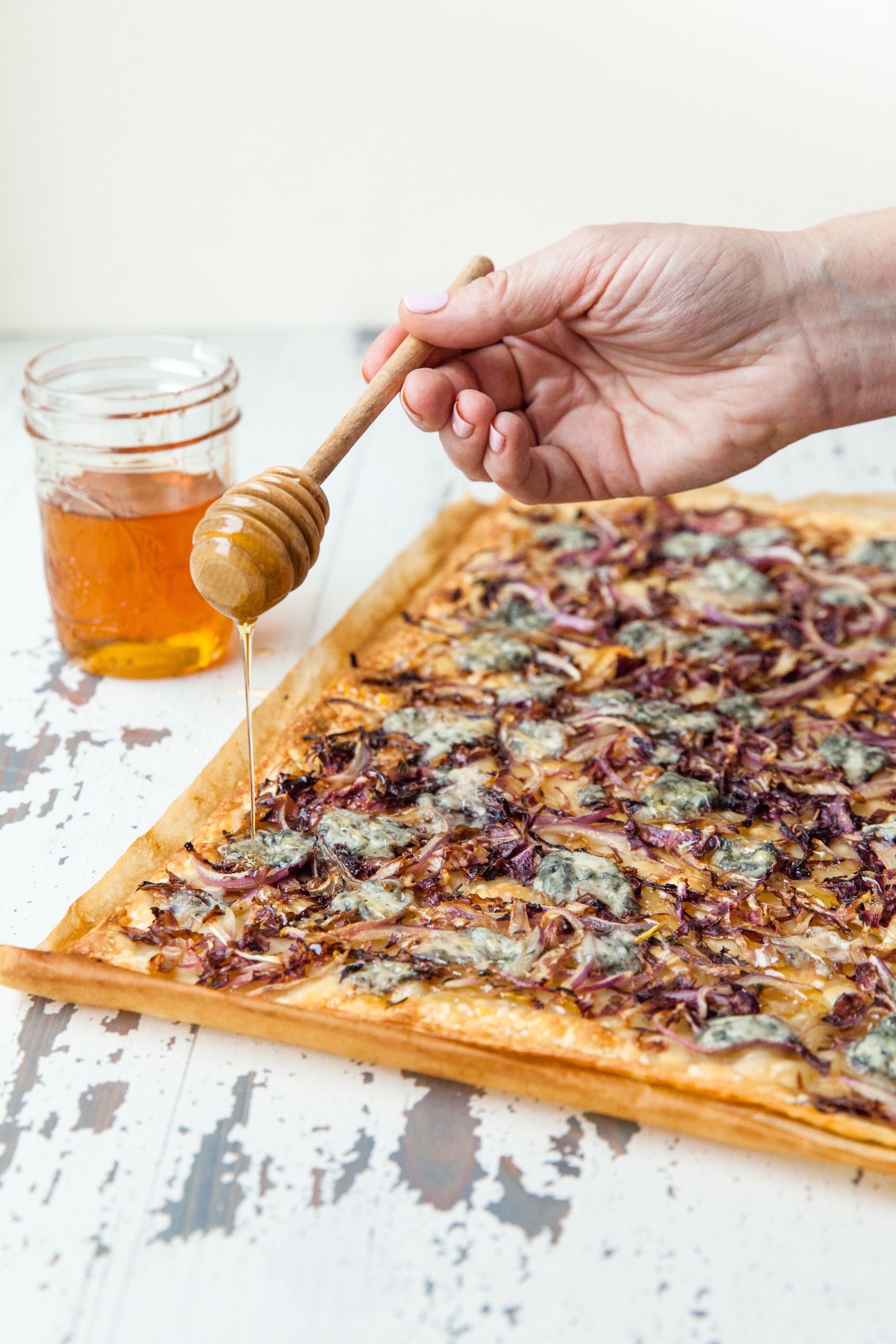 Drizzling honey over flatbread strips with Blue Cheese, Radicchio, and Onion.