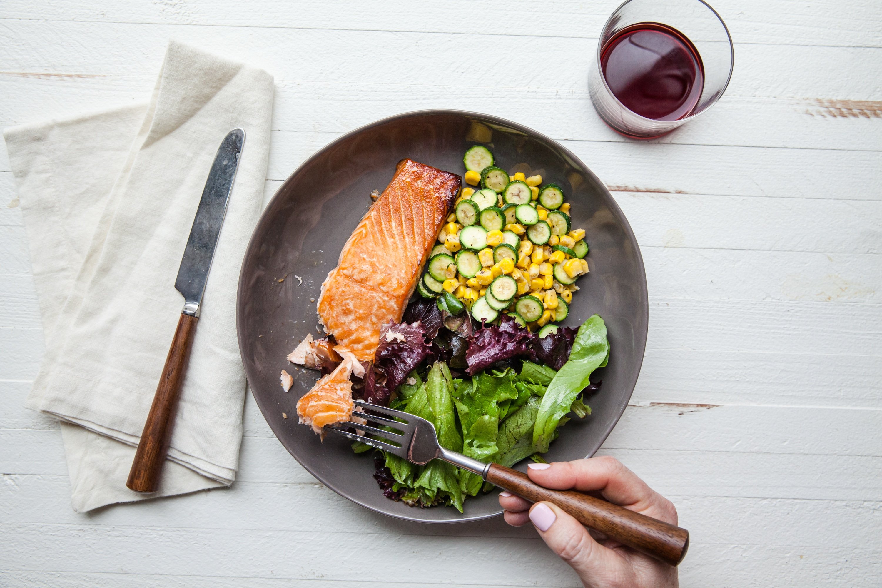 Eating Asian Salmon with Sautéed Corn and Zucchini with fork.