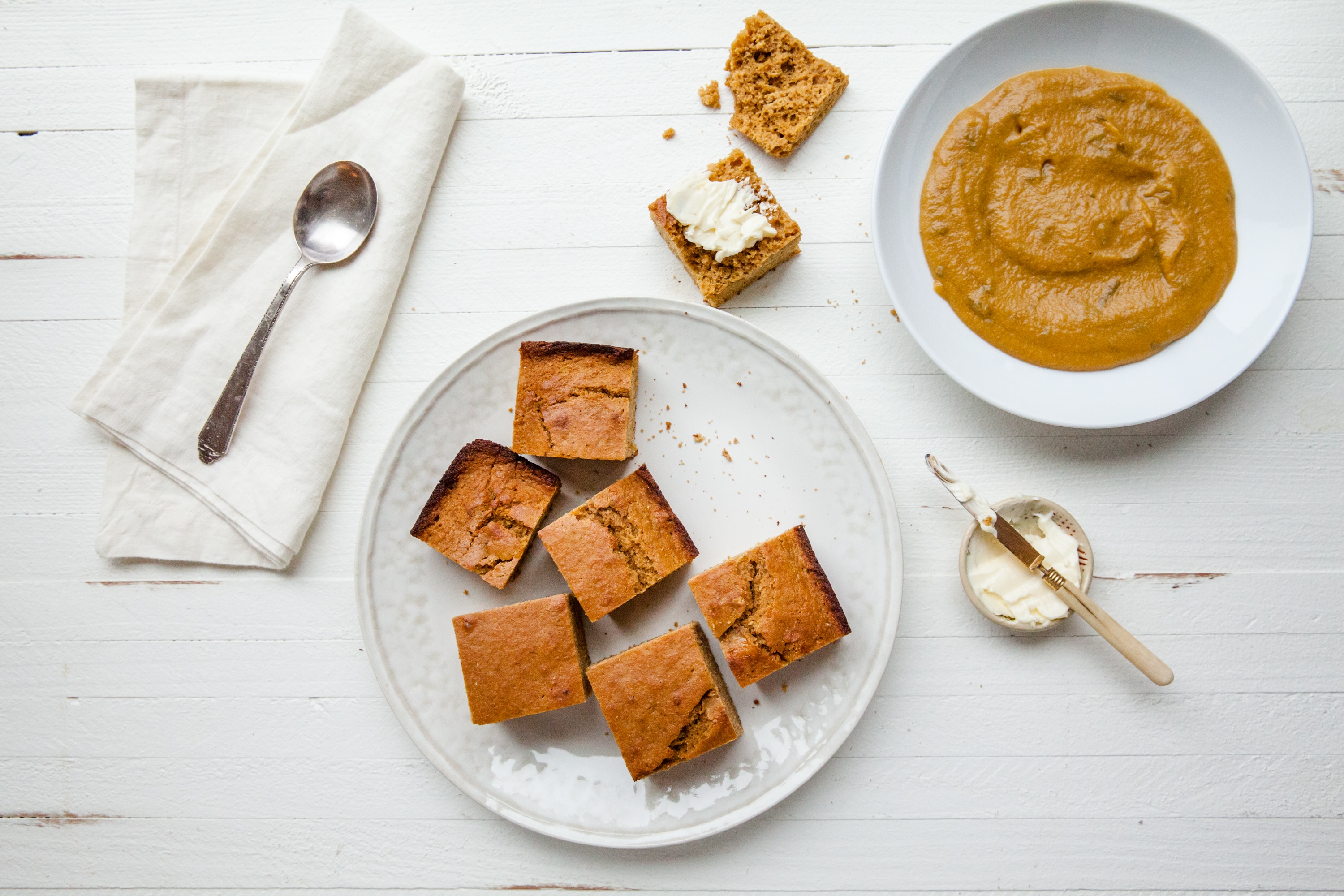 Molasses Cornbread on a plate next to a shallow bowl of soup.