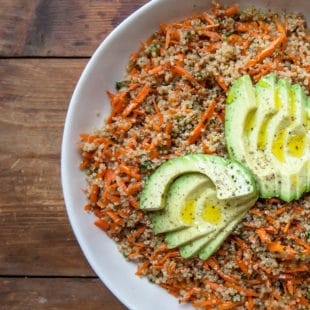Quinoa and carrot salad topped with sliced avocado.