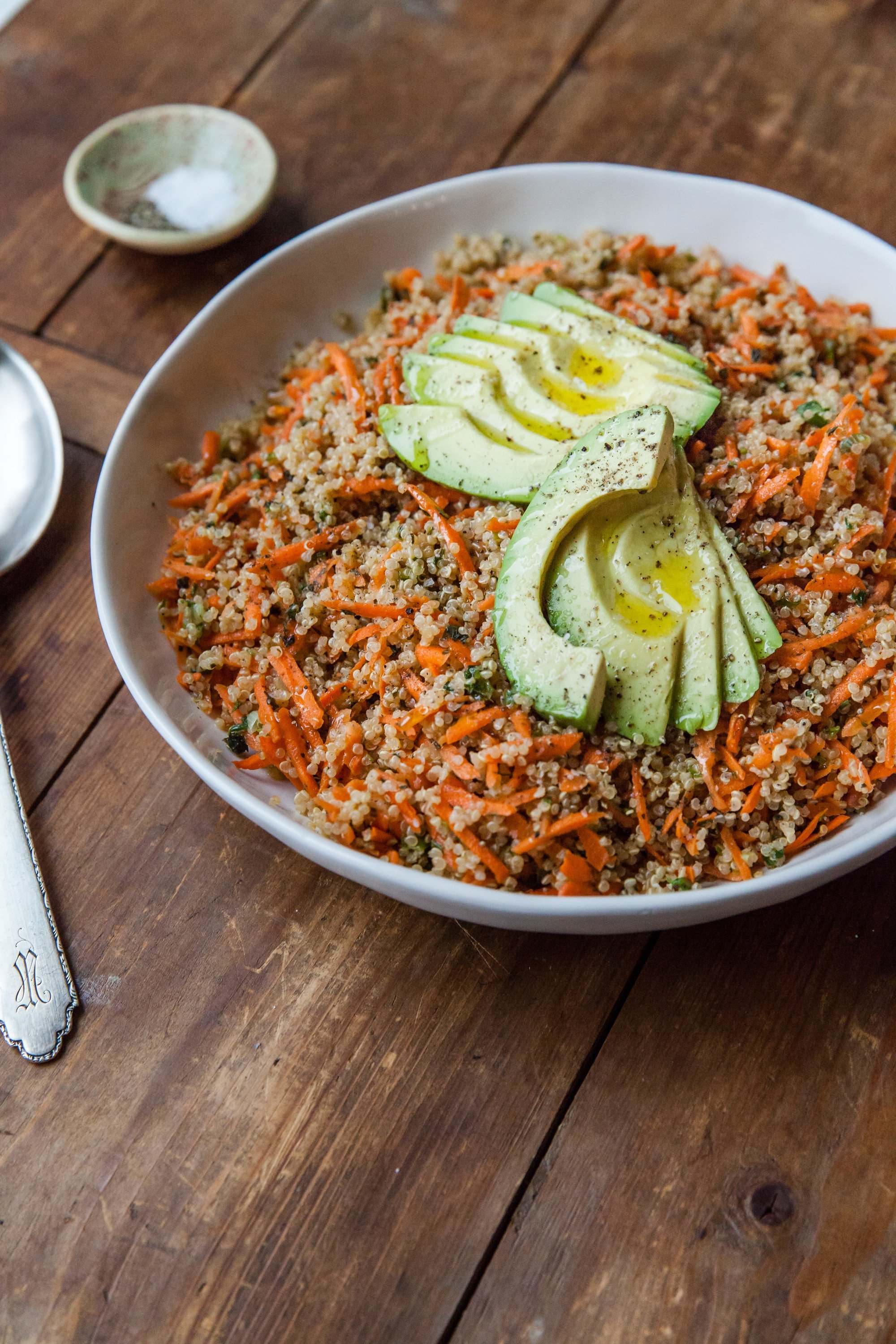 Sesame-Honey Quinoa and Carrot Salad with Sliced Avocado in white bowl.