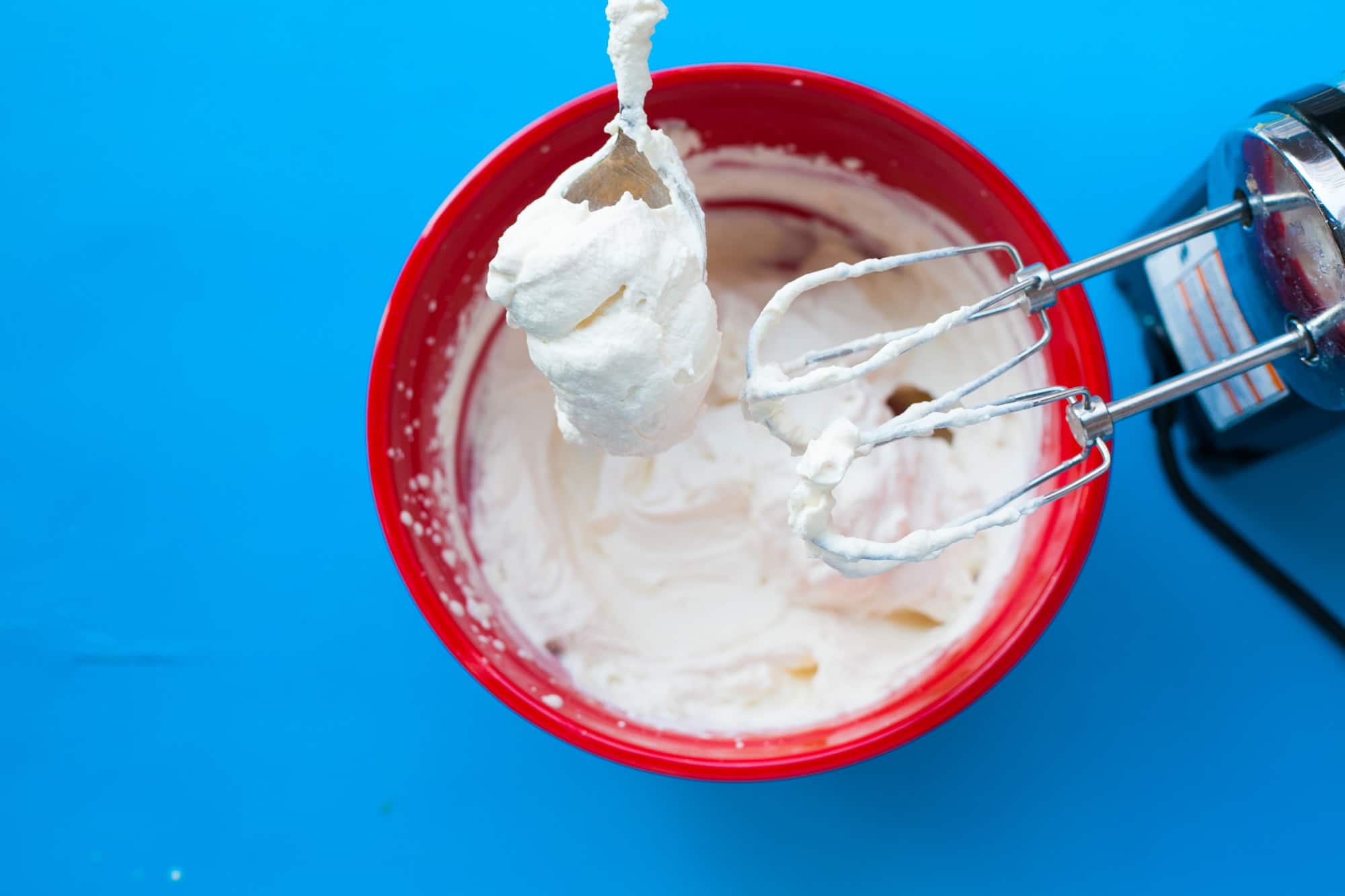 Homemade whipped cream in bowl with mixer.