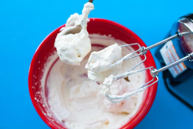 Homemade whipped cream in bowl with mixer.
