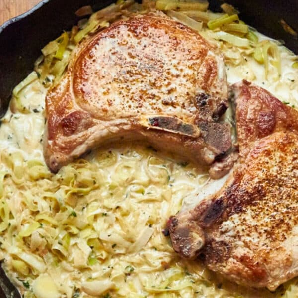 Pork chops with creamy madeira wine sauce in cast-iron pan.