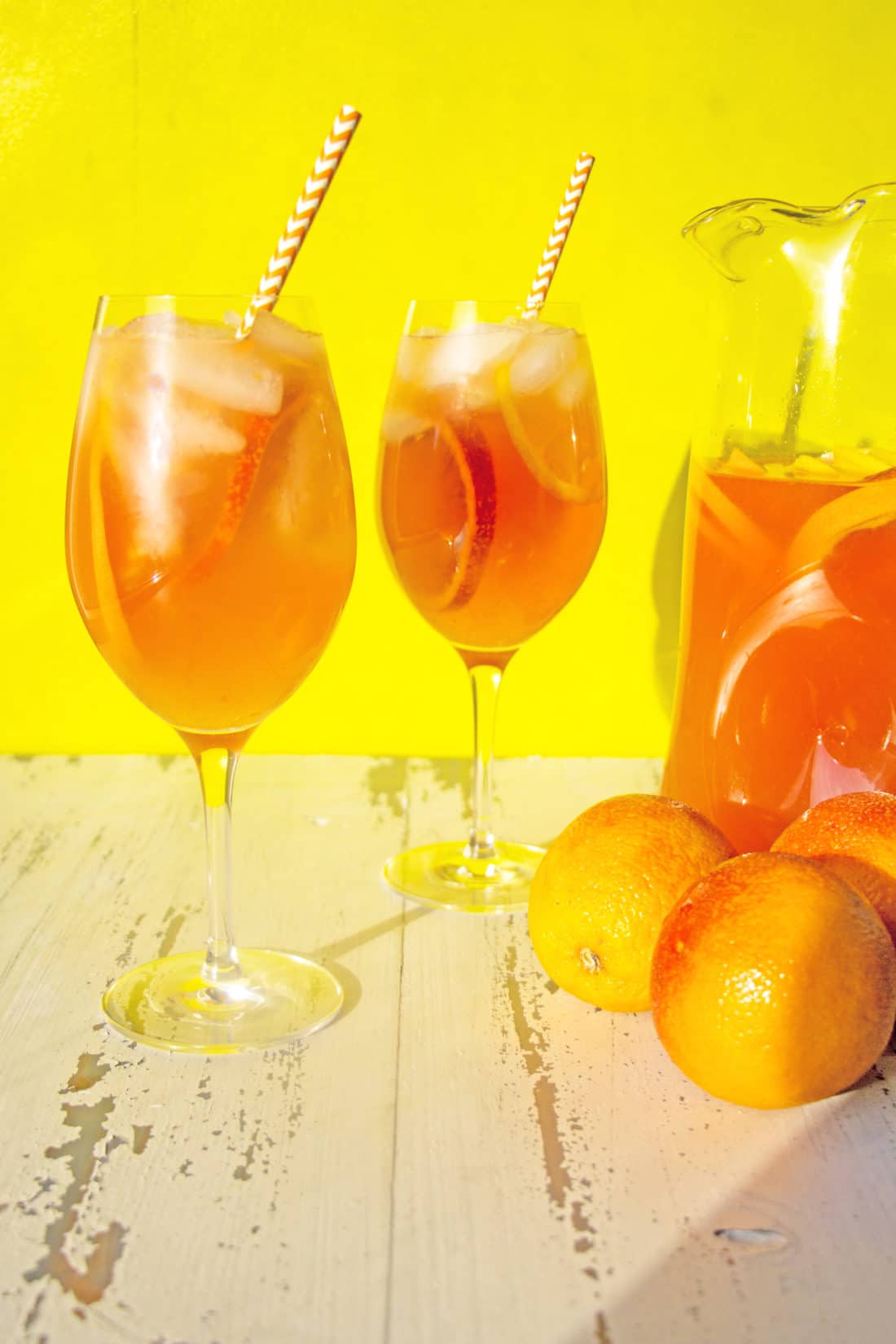 Two long-stemmed glasses of Orange White Wine Campari Sangria.