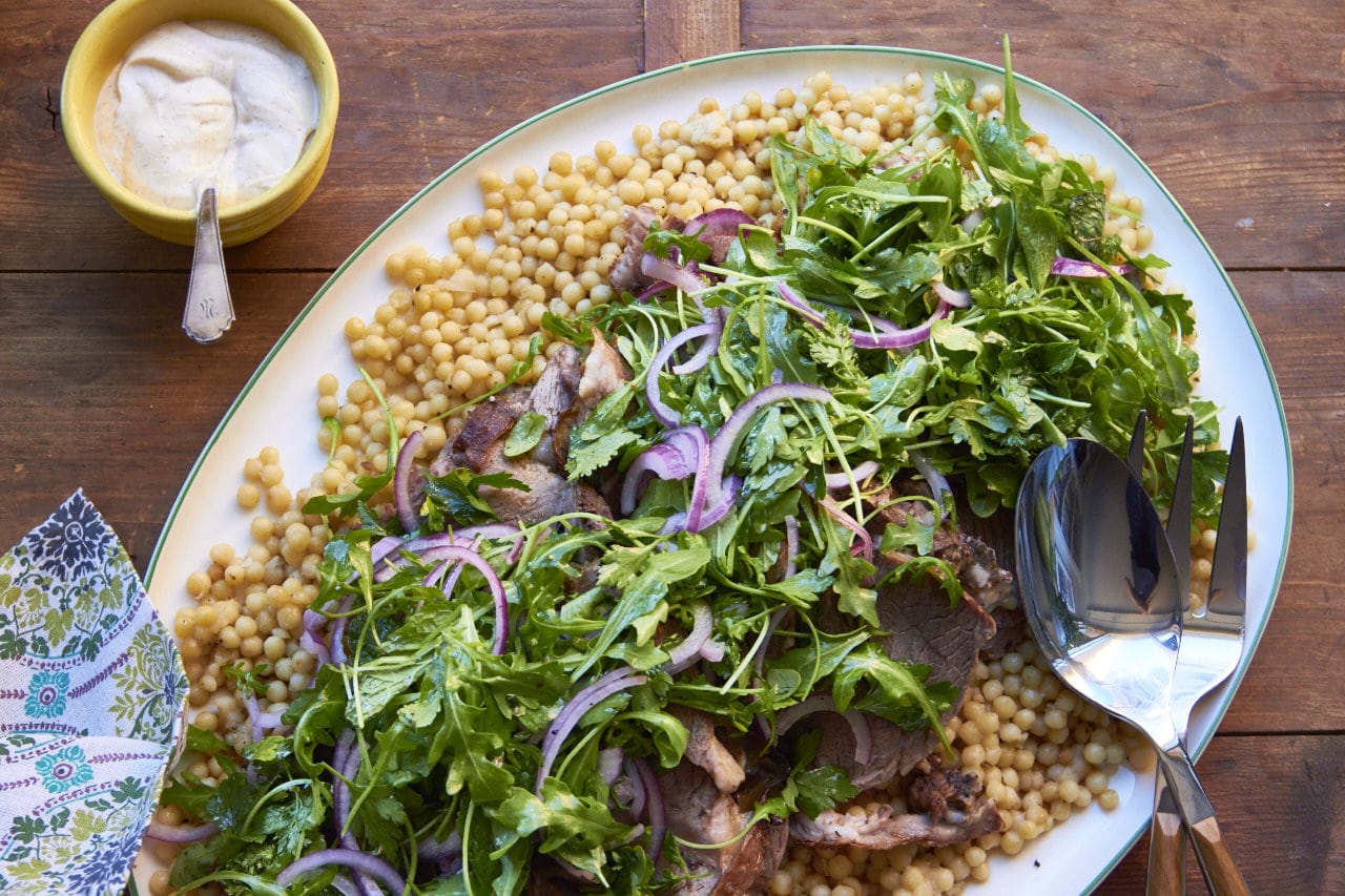 Slow Cooked Herbed Leg of Lamb with Fresh Herb and Arugula Salad on a platter.