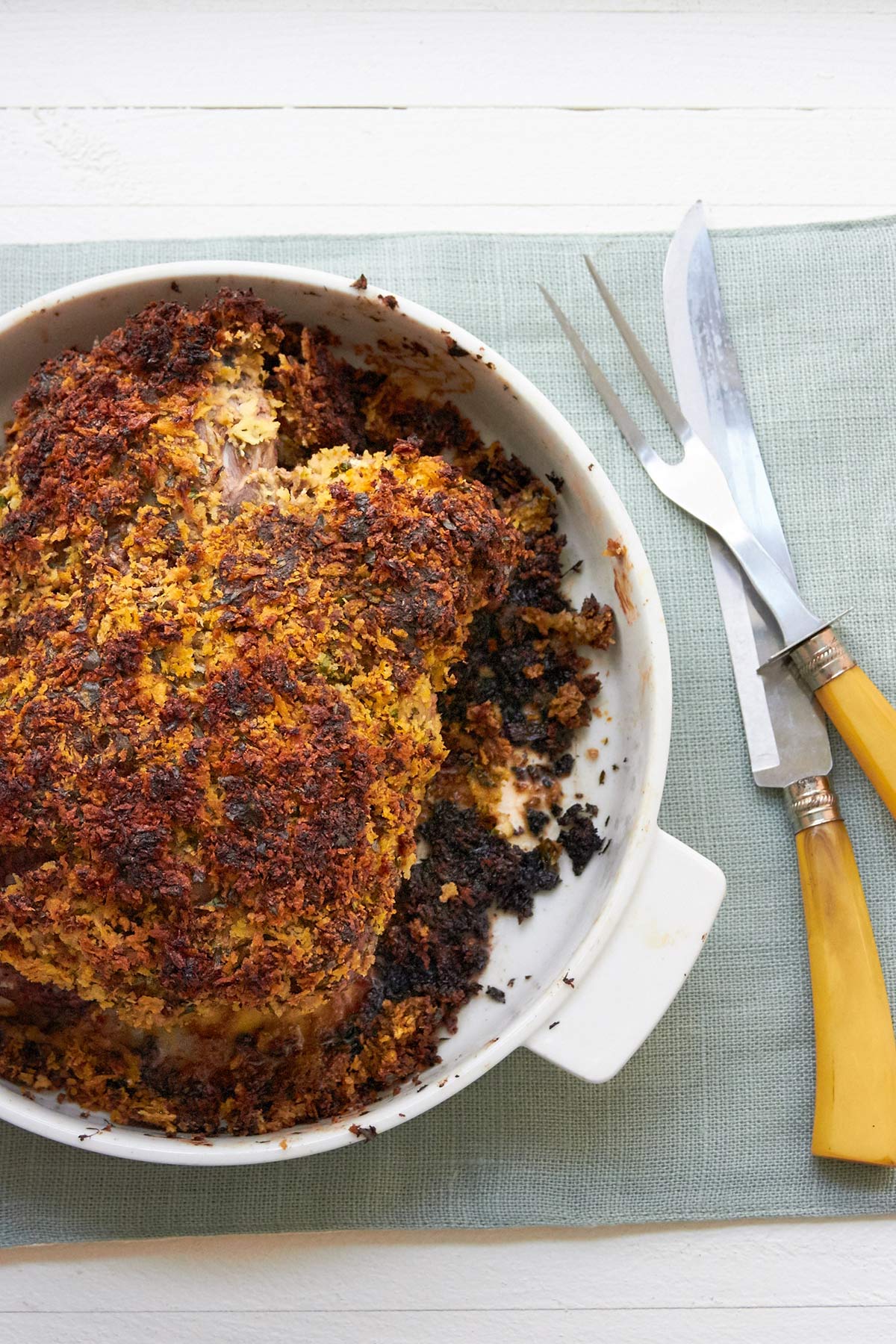 Herbed Boneless Leg of Lamb with Mustard Crust in baking dish on table.
