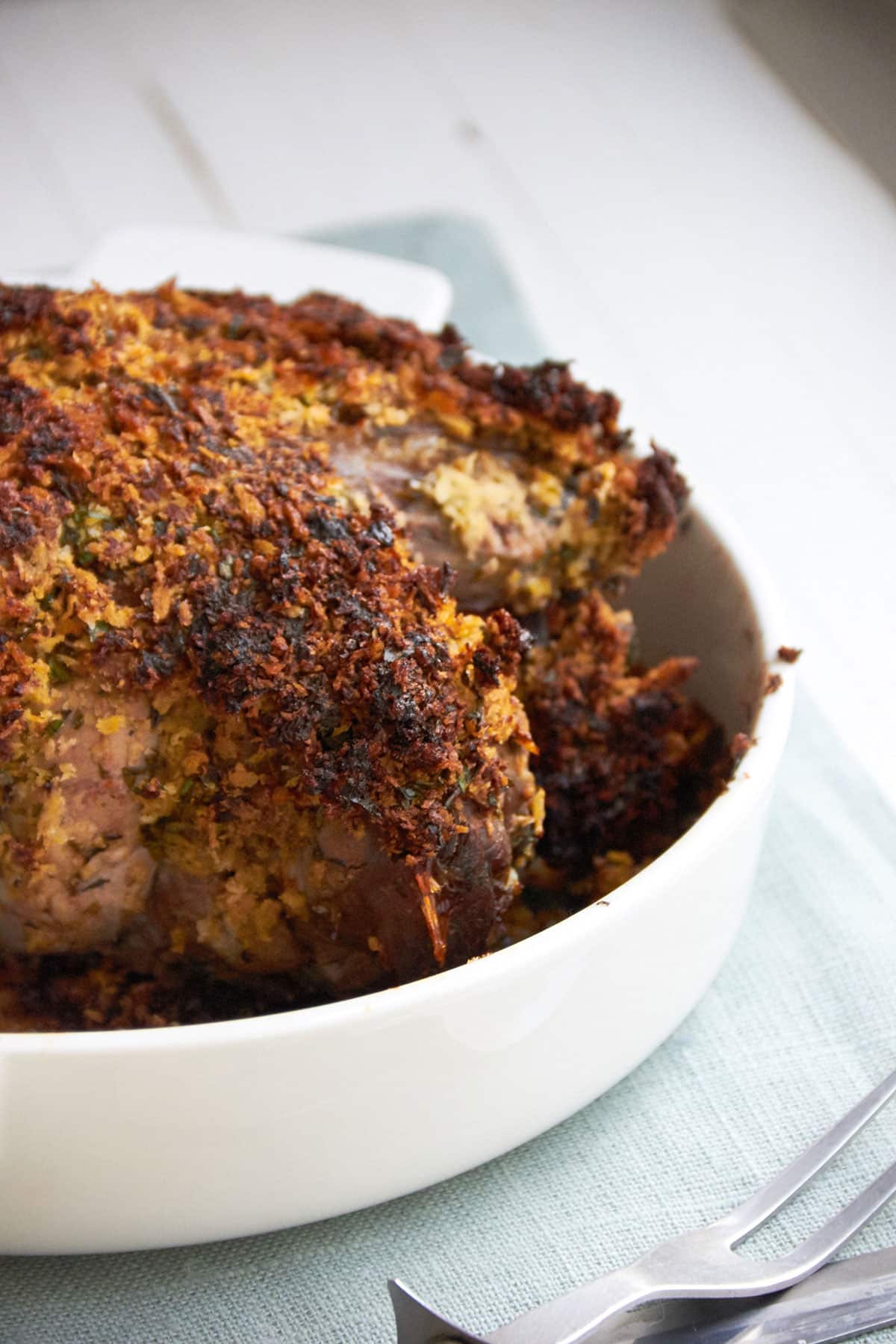 Herbed Boneless Leg of Lamb with Mustard Crust in a white bowl.