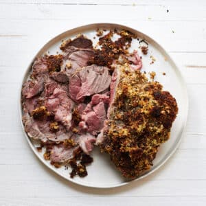 Herbed Boneless Leg of Lamb with Mustard Crust sliced on platter.