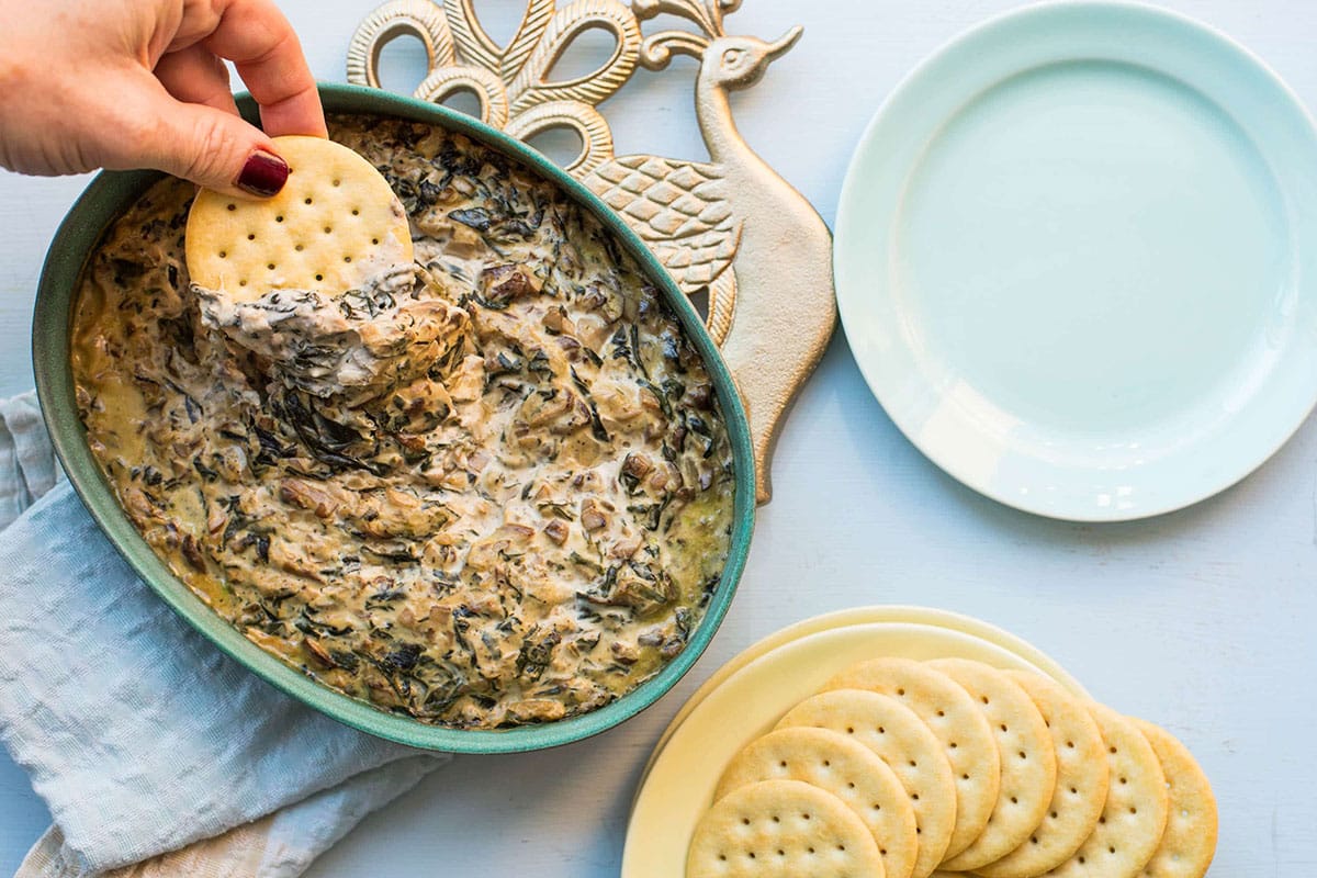 Spinach and Goat Cheese Dip in baking dishes with bowl of tortilla chips