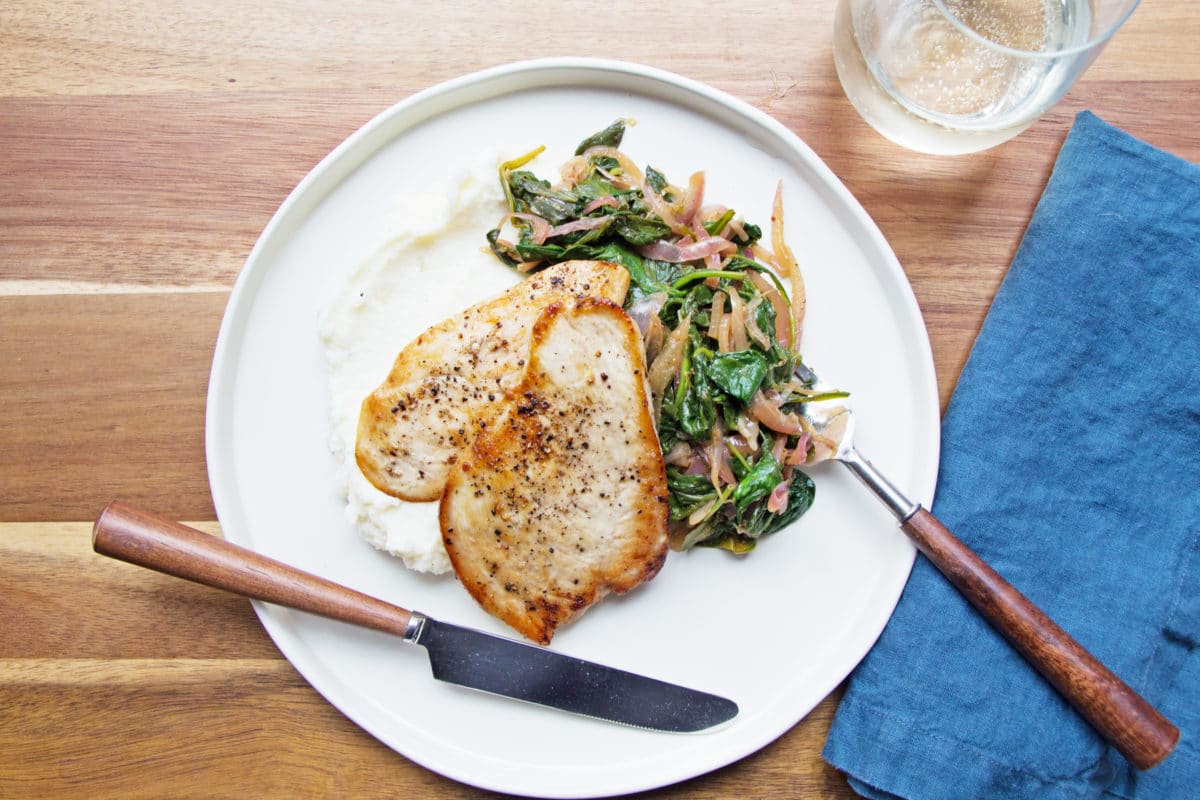 Fork on a plate with Sautéed Chicken with Spinach and Red Onions.