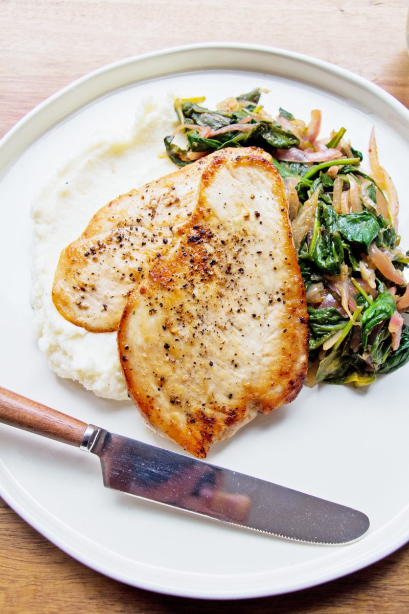 Sautéed Chicken with Spinach and Red Onions on a plate with a knife.