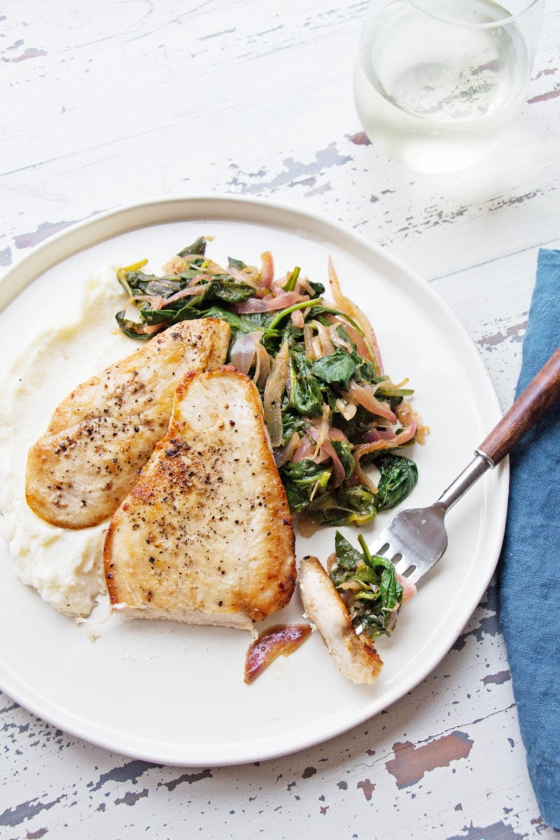 Fork with a bite of Sautéed Chicken with Spinach and Red Onions.