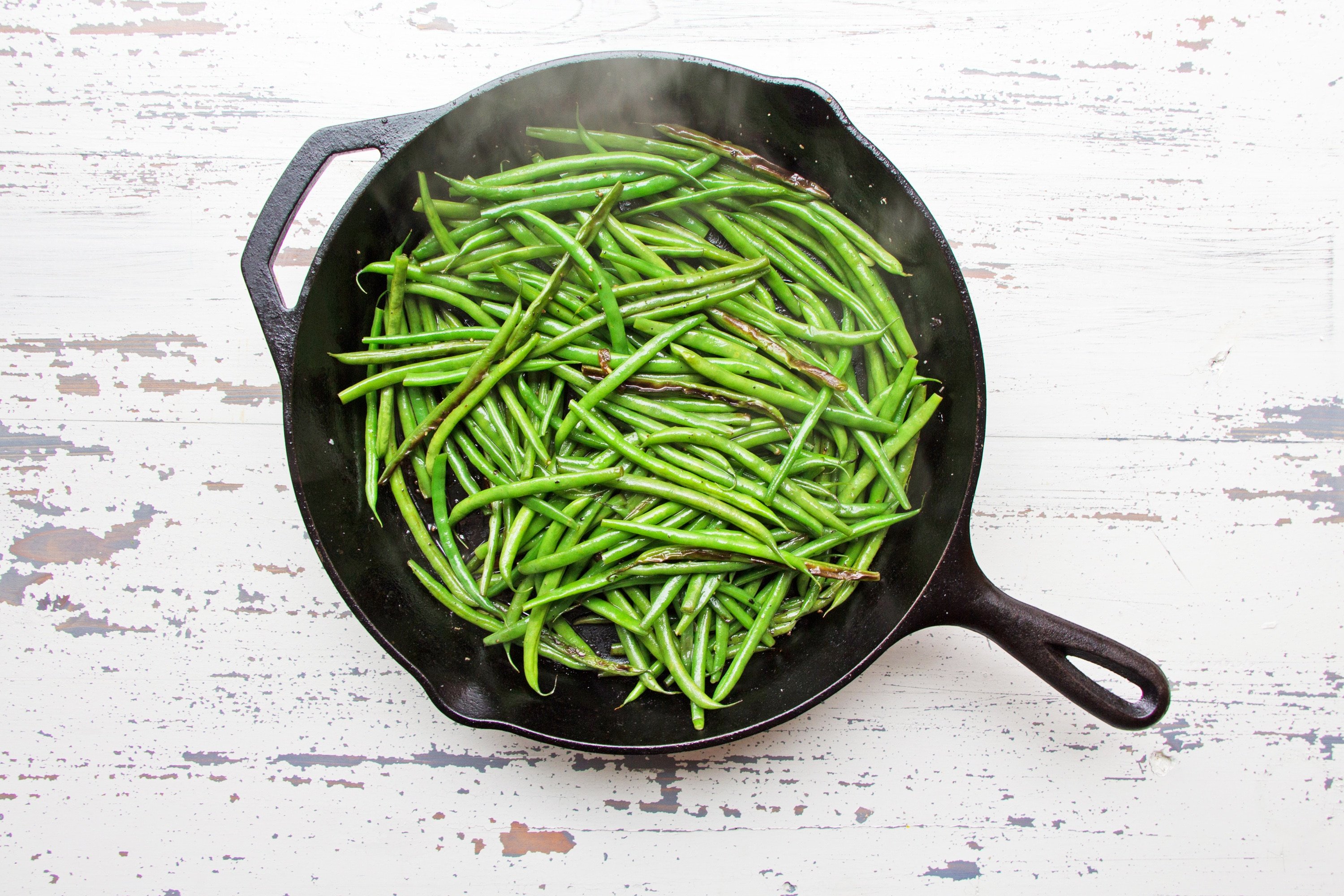 Sautéed Haricot Verts in steaming hot cast iron pan.