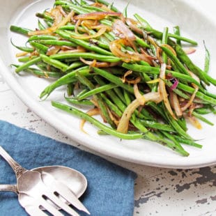 Sautéed Haricot Verts with Red Onions and Shallots piled high on a white dish.