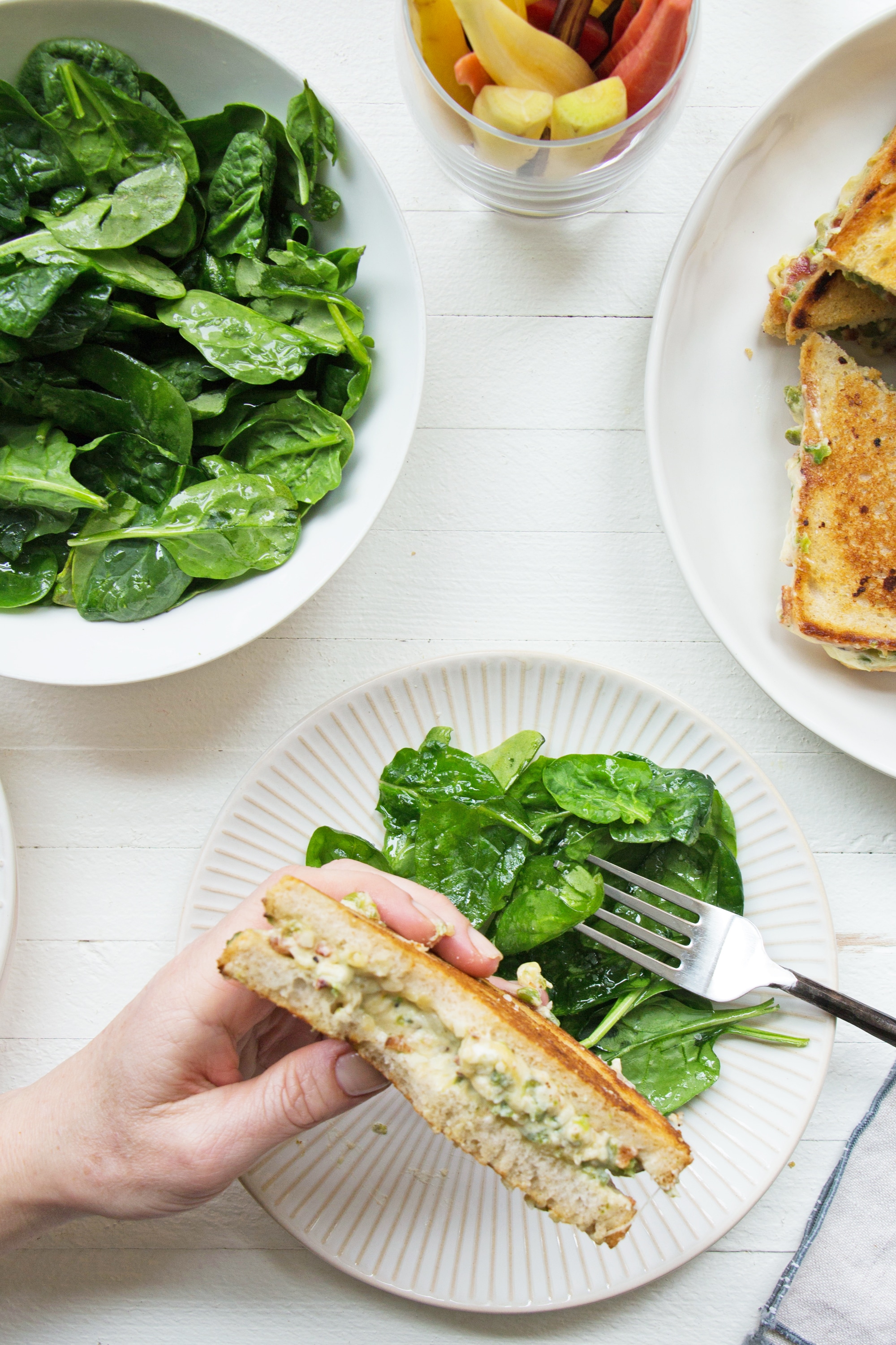 Woman holding a Jalapeno Popper Grilled Cheese sandwich over a plate of salad.