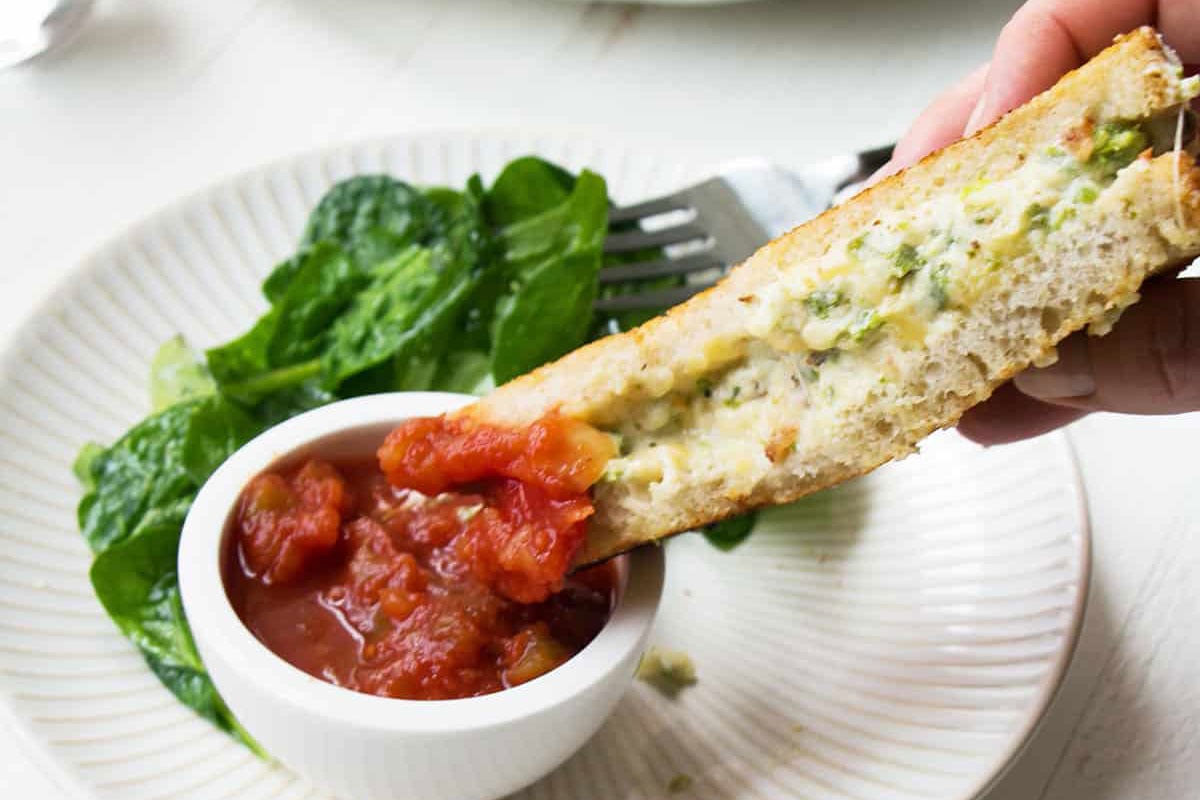 Jalapeno Popper Grilled Cheese sandwich dipping into salsa.