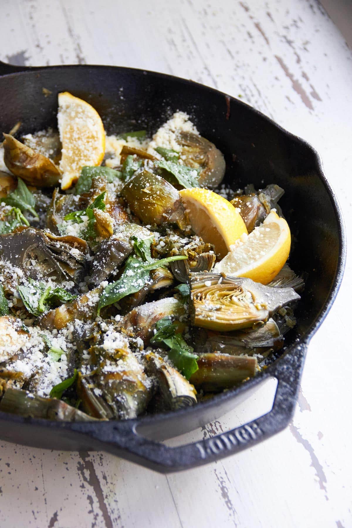 Braised Baby Artichokes with Leeks and Capers in a skillet.