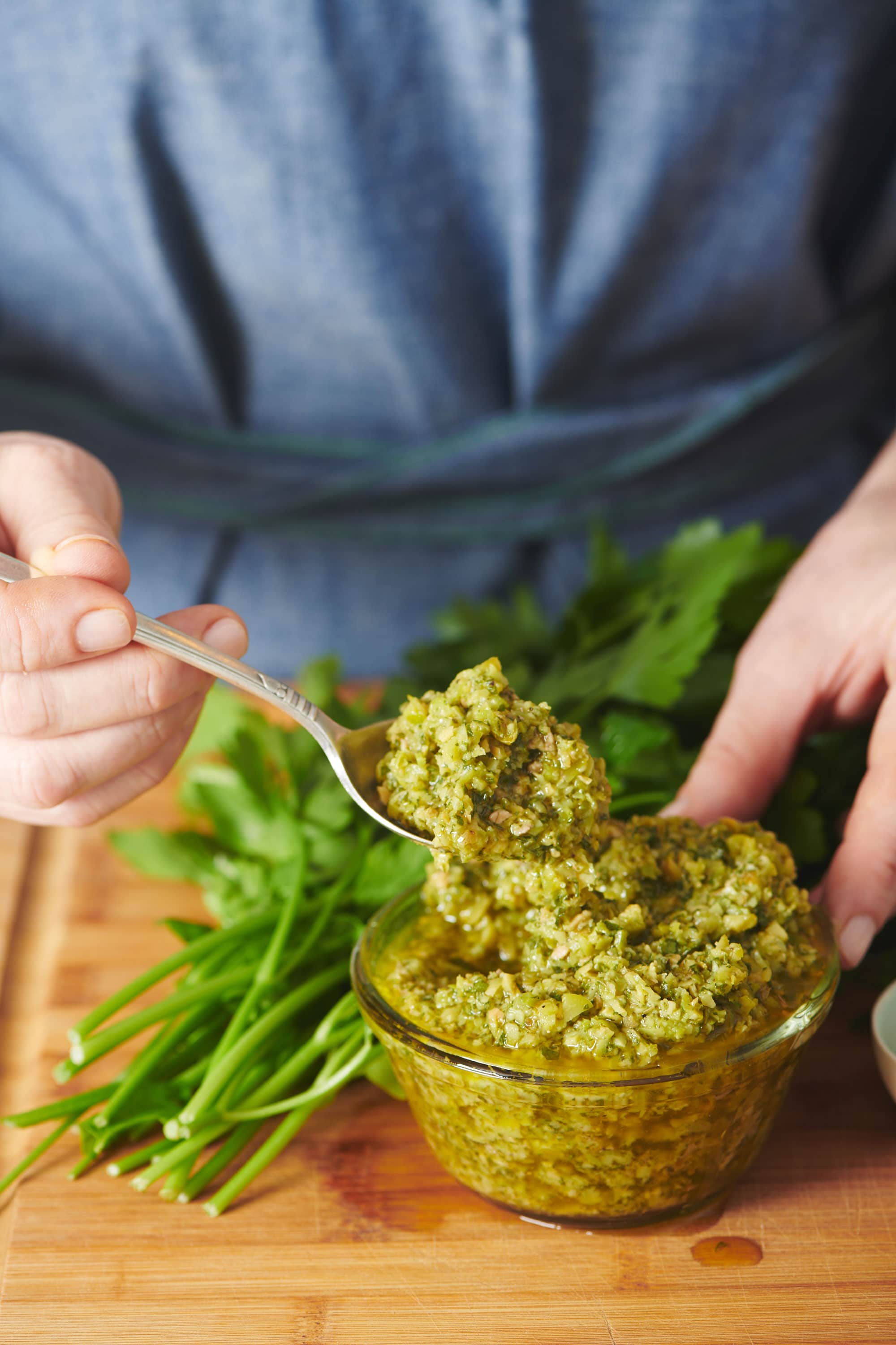 Woman scooping up a spoonful of Green Olive Tapenade.