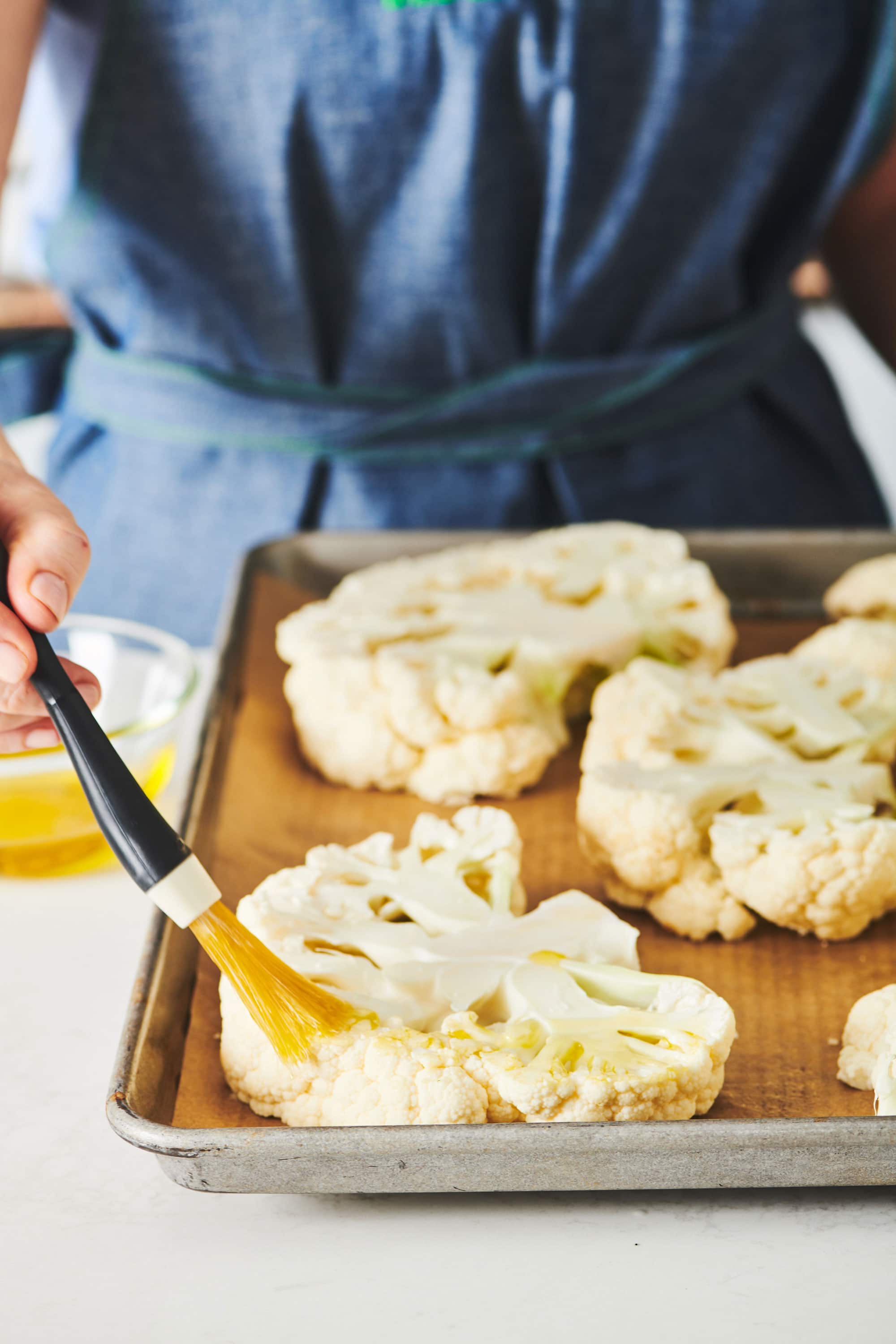 Woman spreading butter on cauliflower slices.