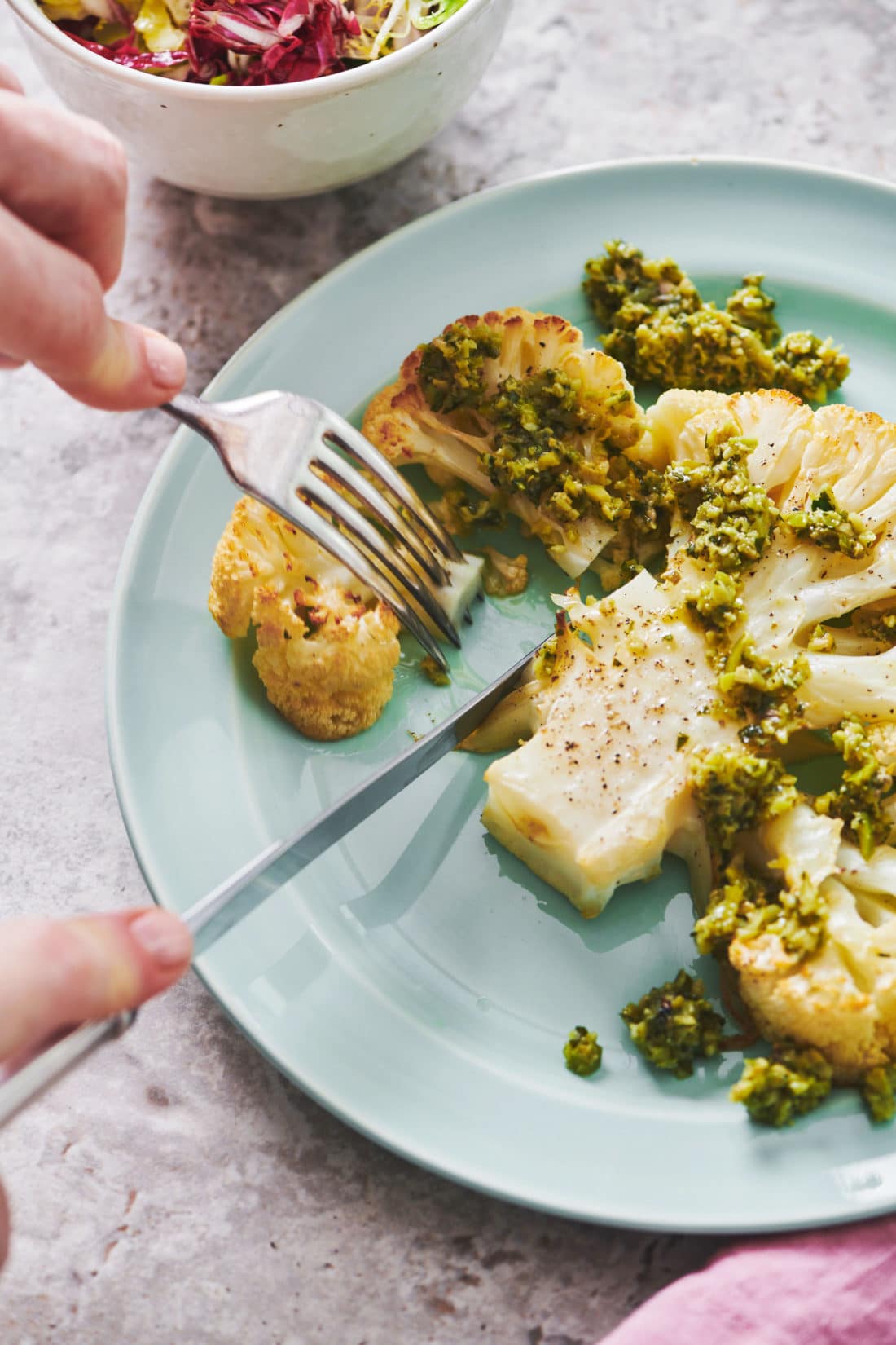 Fork grabbing a piece of Roasted Cauliflower Steak with Tapenade.