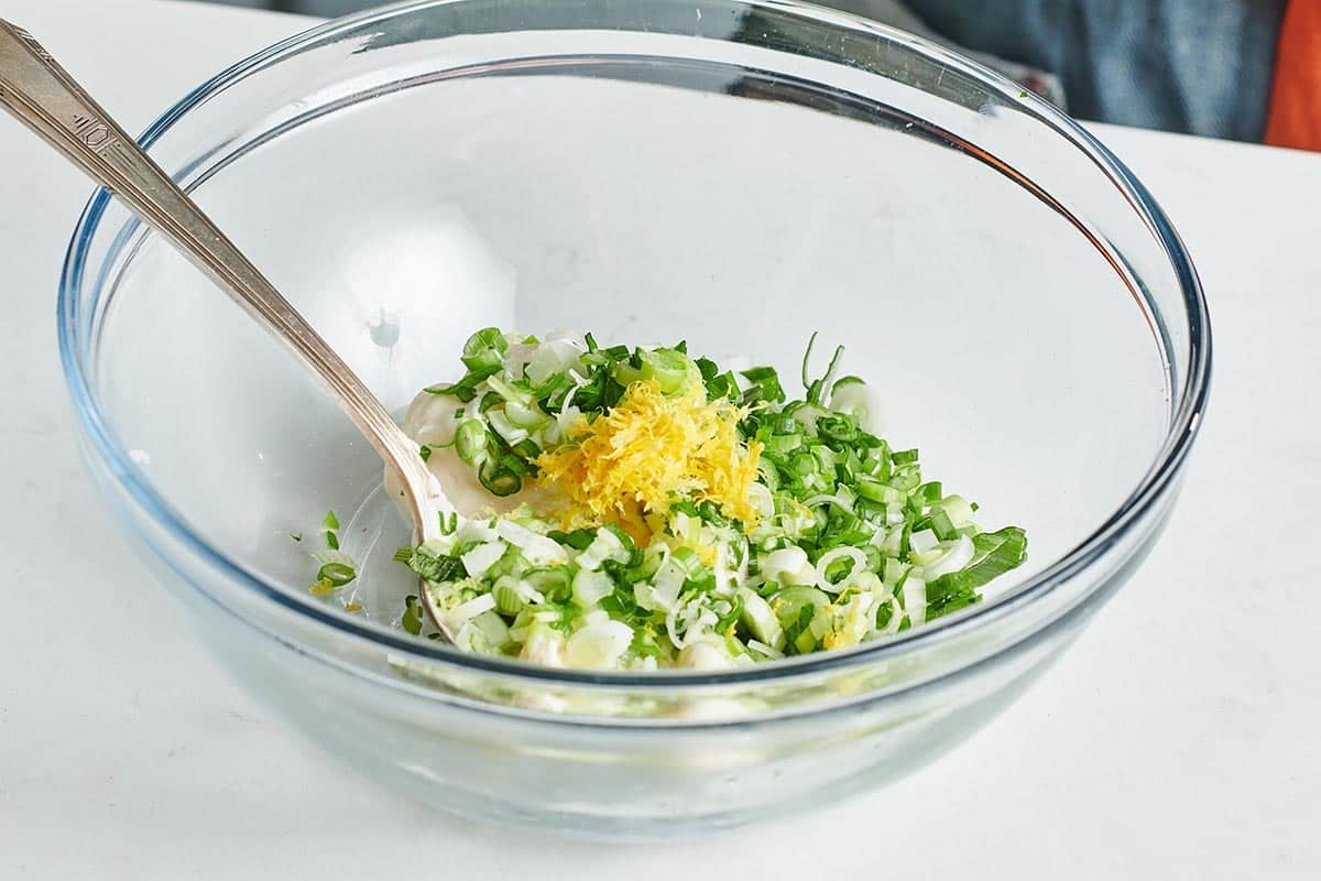 Scallions and lemon zest in a glass bowl.