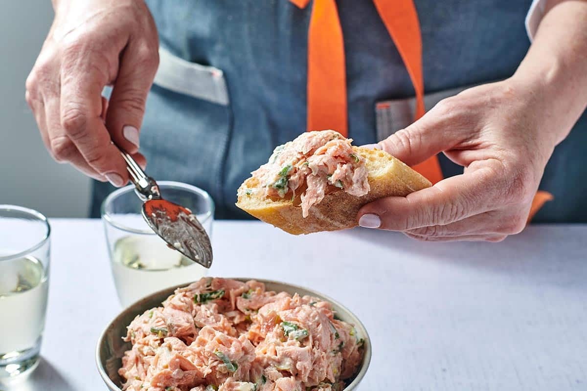 Woman using a butter knife to put Salmon Spread on bread.
