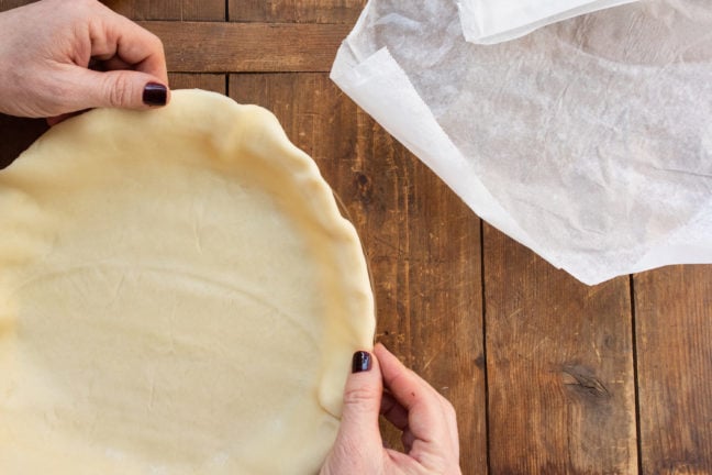 Woman molding the edges of a pie crust.