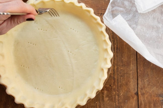 Pricking pie crust with a fork before blind baking