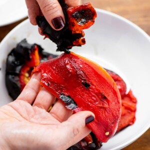 Woman removing the skin from a roasted red pepper.