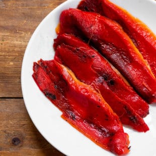 Roasted red peppers on a white plate.