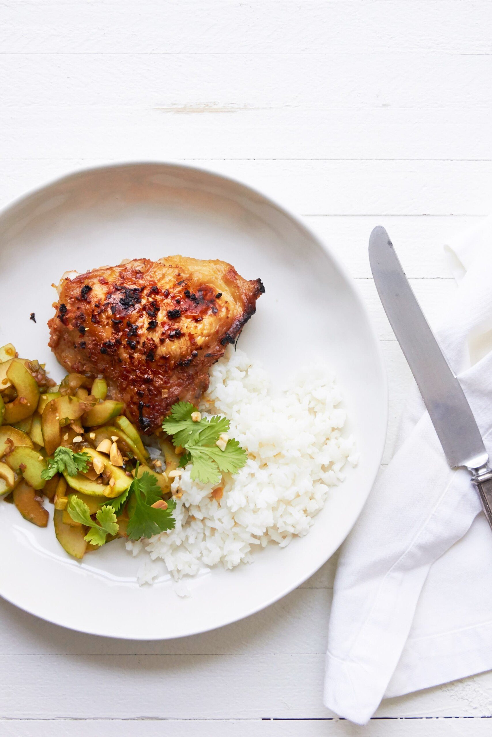 Thai Chicken Thighs with Thai Cucumber Salad and rice on white plate.