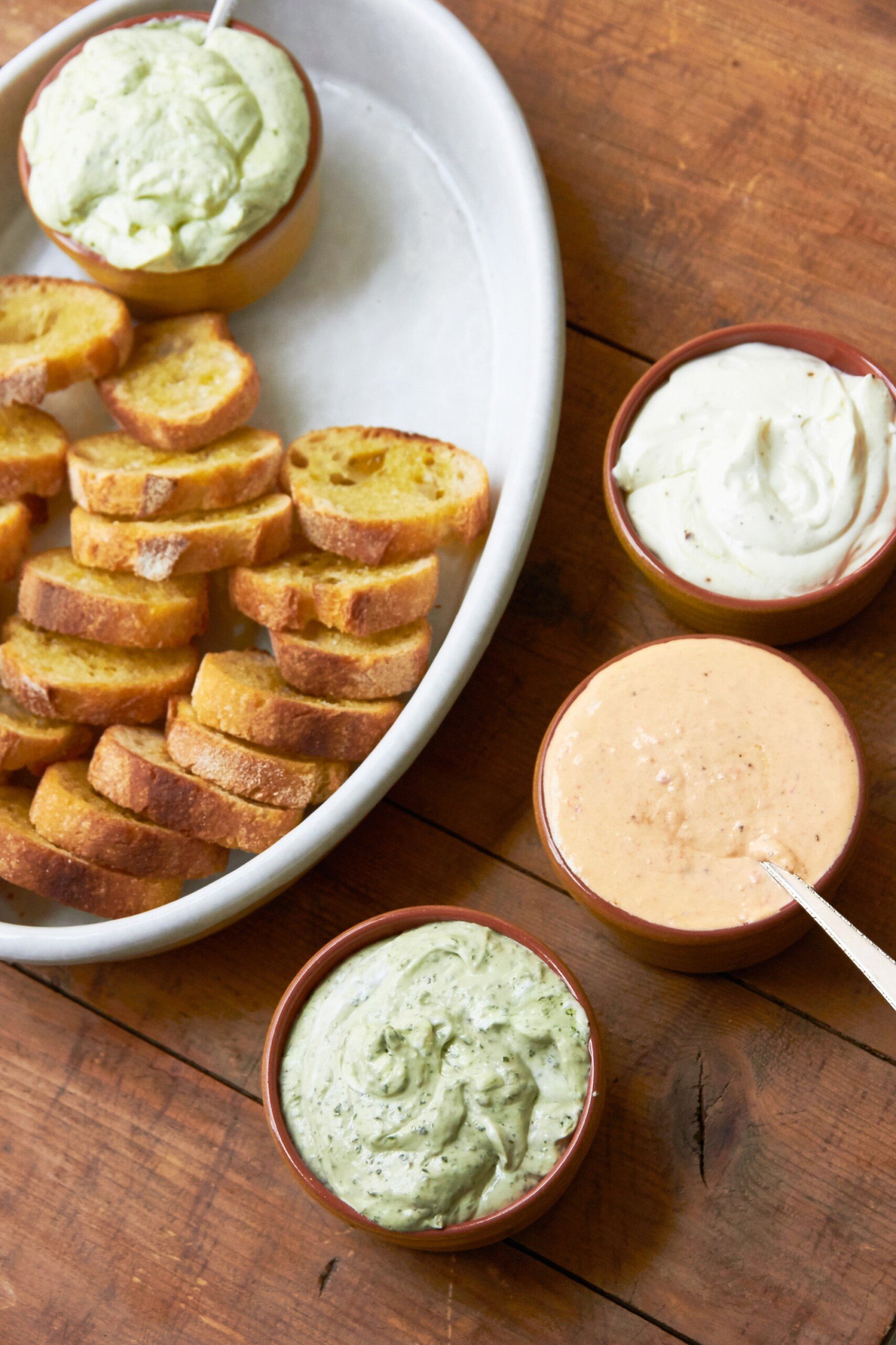 Tray of sliced bread with four bowls of dips.
