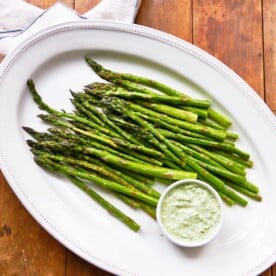 Asparagus with Herb Dipping Sauce on white plate.