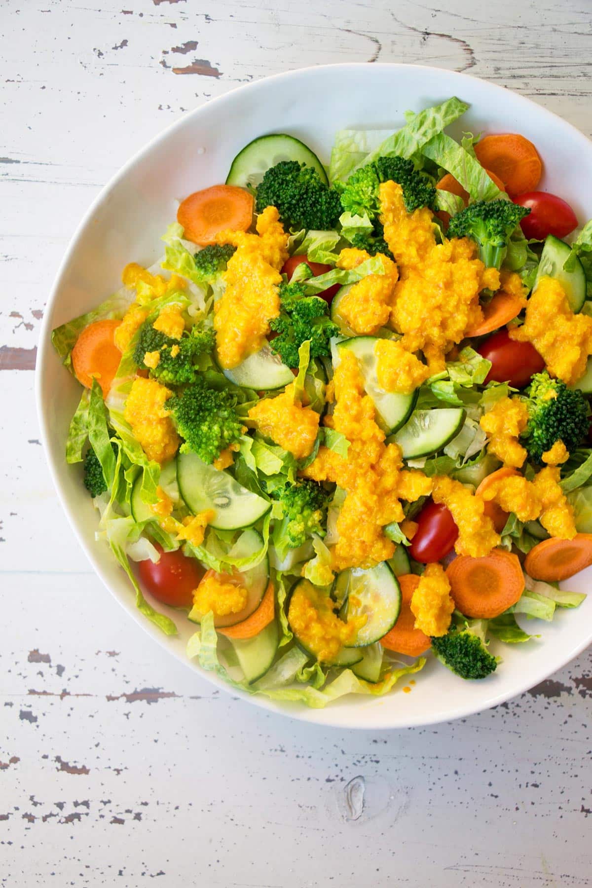 Leafy salad on white plate with Japanese-style dressing.