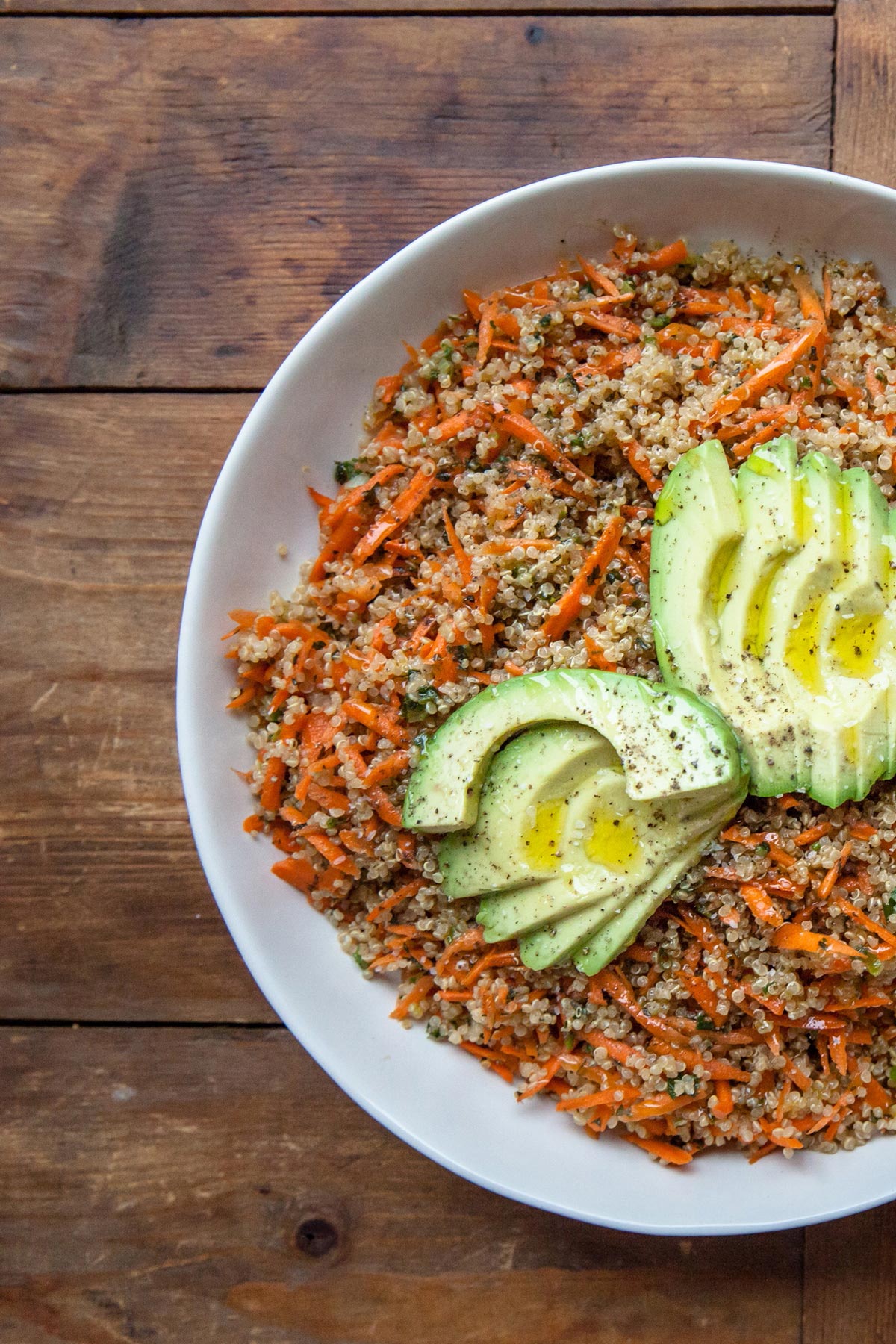 Bowl filled with Sesame-Honey Quinoa and Carrot Salad topped with Sliced Avocado.
