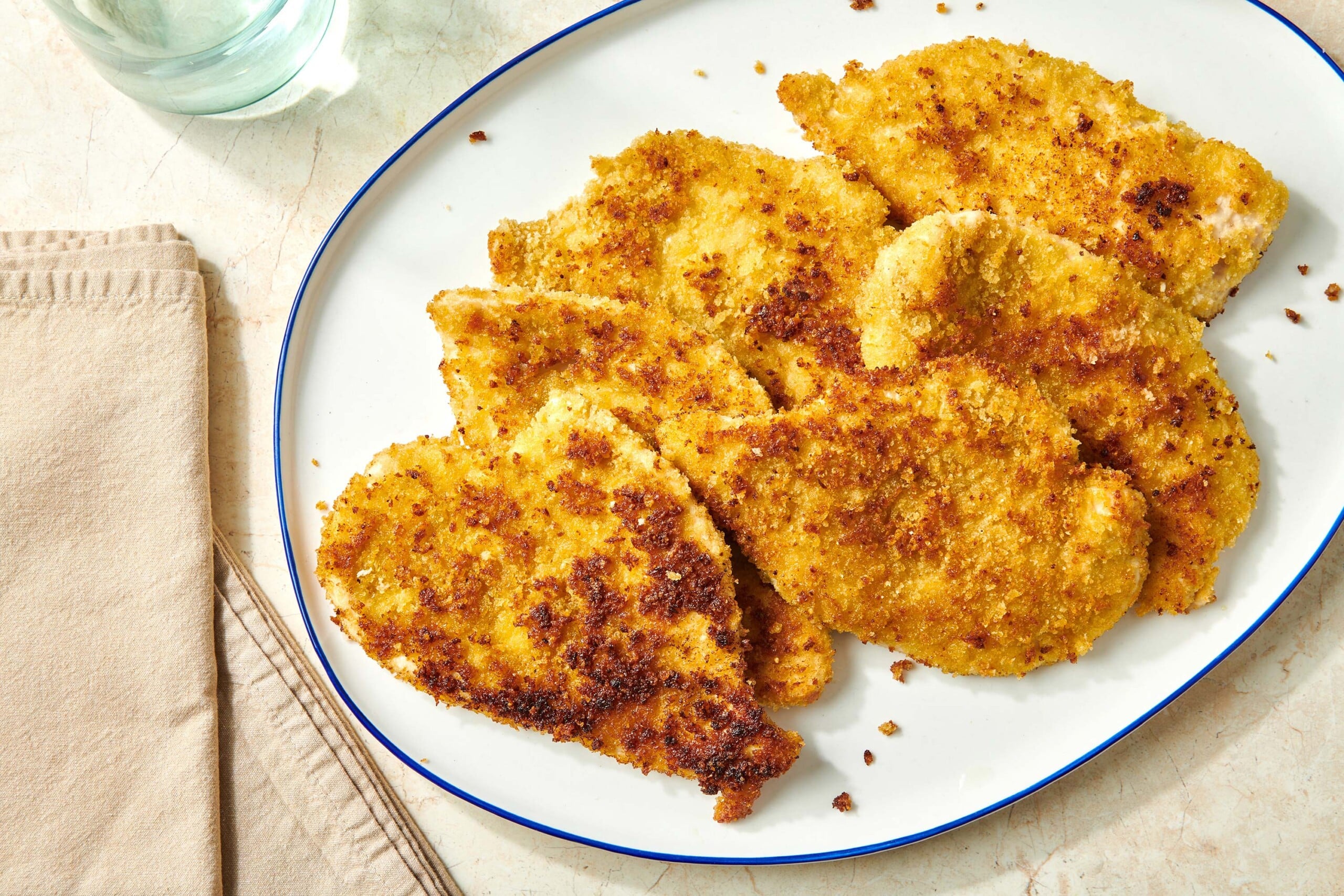 Cooked breaded chicken cutlets on white plate.