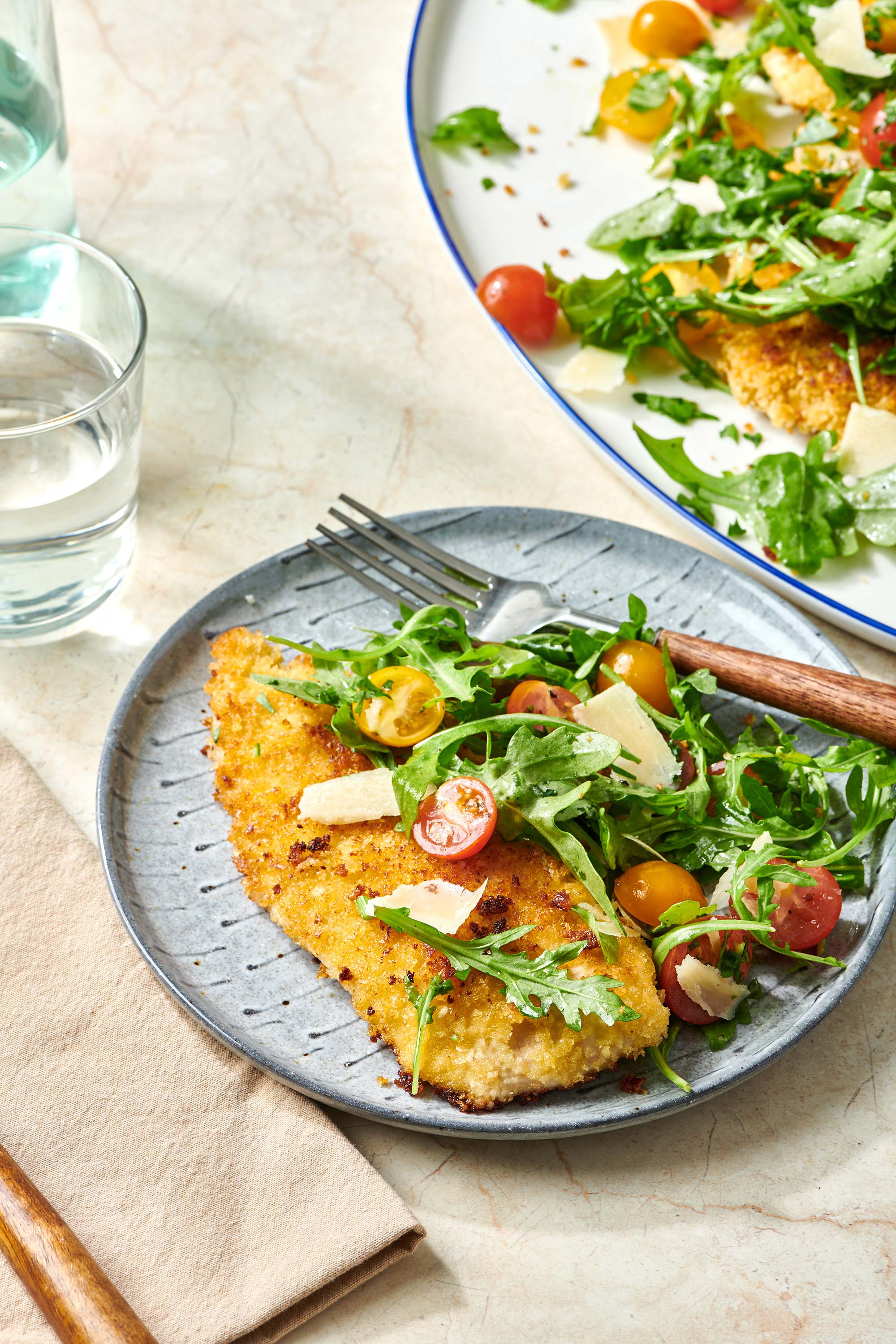 Fork on a plate with Chicken Milanese and salad.