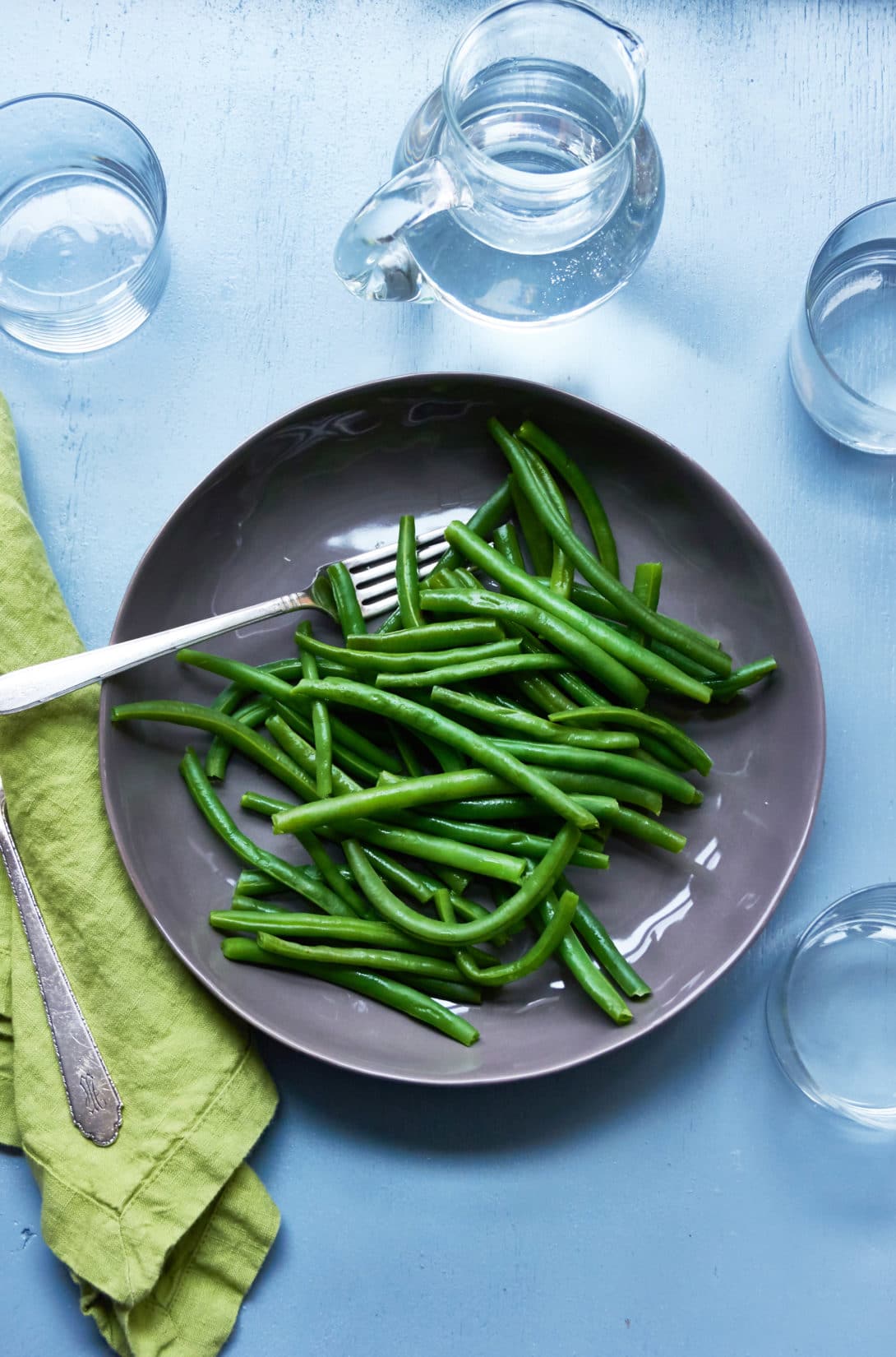 Dark grey bowl of Green Beans with a fork.