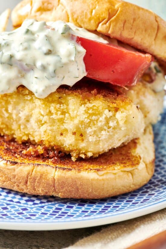 Fried Fish Sandwich with tartar sauce and a slice of tomato.