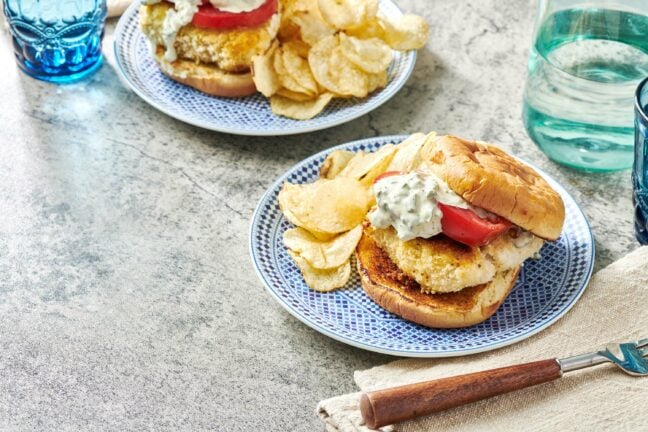 Plates of Fried Fish Sandwiches and chips set on a table.