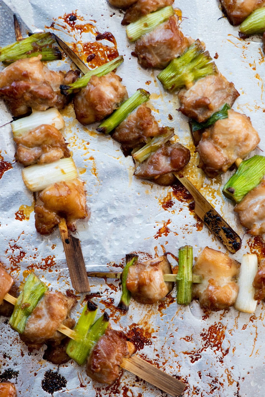 Chicken Yakitori skewers on a lined baking sheet.